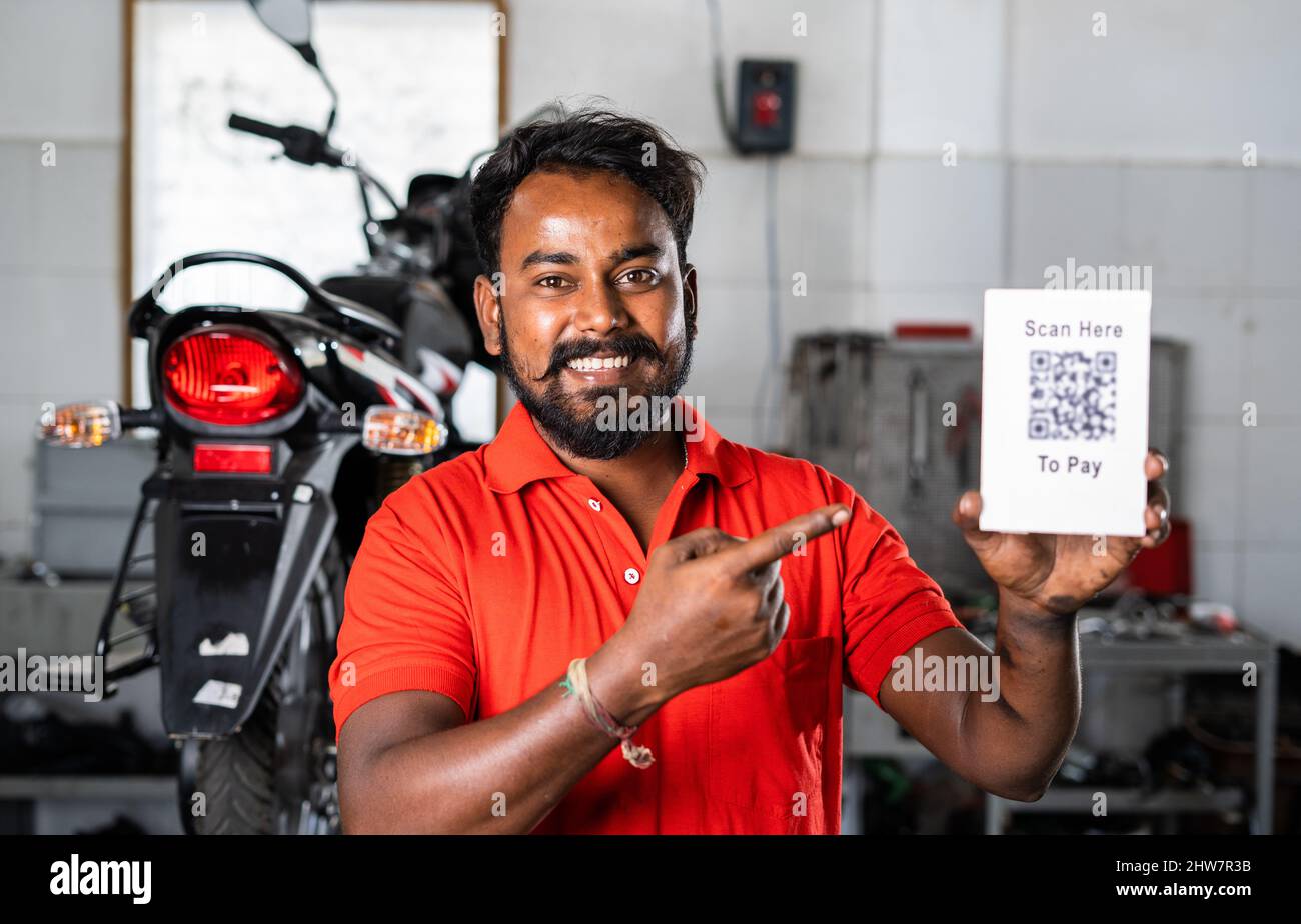 Il meccanico della moto consiglia mostrando la scansione qui per pagare il cartello QR codice dopo il servizio di riparazione - concetto digitale contatto meno pagamento, senza contanti Foto Stock