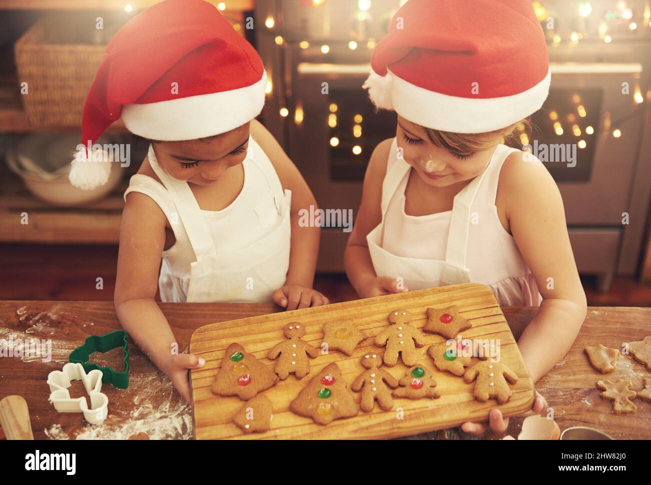 Santas piccoli aiutanti. Shot di due bambine che cucinano biscotti di Natale in cucina. Foto Stock