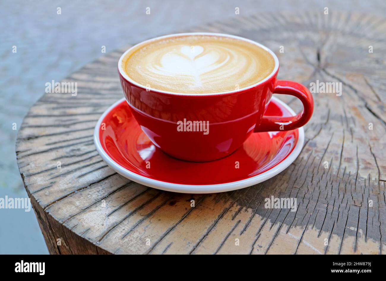 Un caffè Hot Cappuccino in Red Cup servito sul tavolo Tree Stump Foto Stock