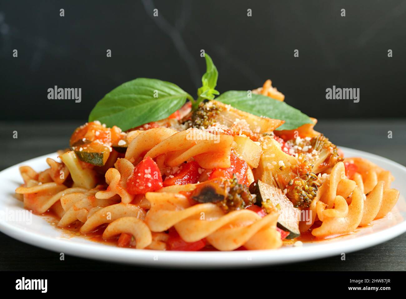 Primo piano di deliziosa pasta di Fusilli integrale in salsa di pomodoro servita su sfondo nero Foto Stock
