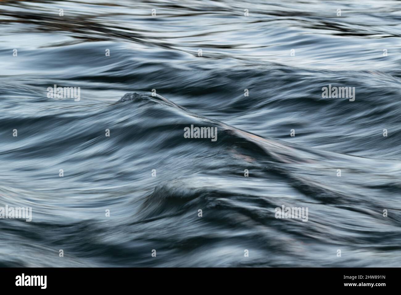 Paesaggio astratto di acqua turbolenta ondulata nel vento con superficie setosa a lunga esposizione ed effetto di sfocatura del movimento Foto Stock