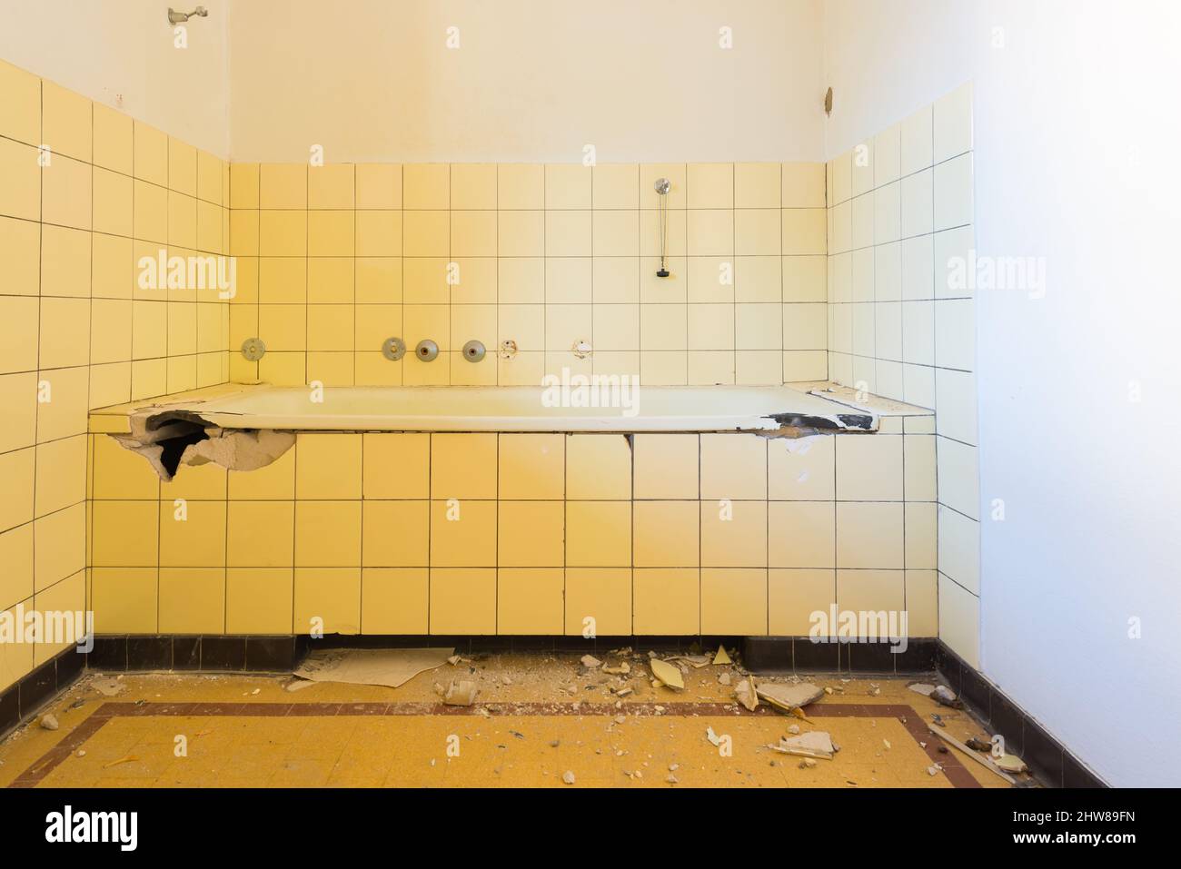 Il bagno è rotto. Pezzi di piastrelle in ceramica e spazzatura sul pavimento. Il tappo dell'acqua è appeso alla parete. Foto Stock