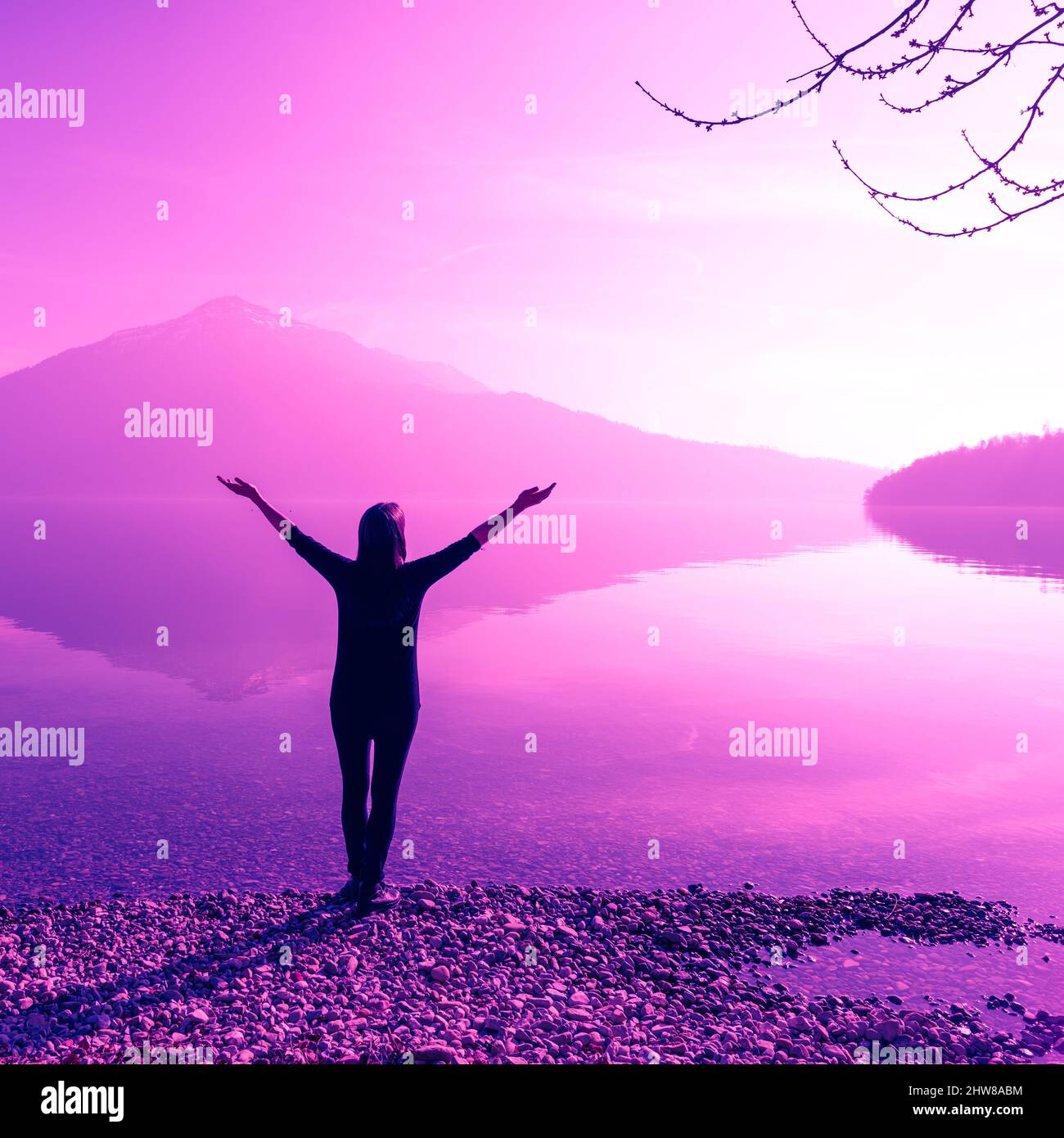 Figura femminile con bracci aperti larghi. Fantastiche vette naturali di montagna riflesse nelle acque del lago. La luce del sole. Foto Stock