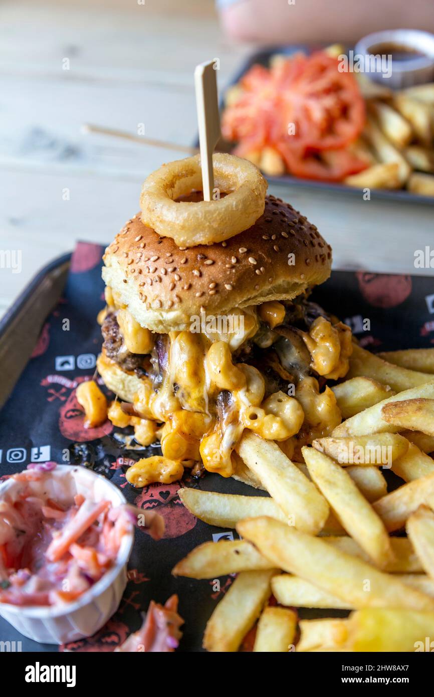 Mac Attack Burger sormontato con mac e formaggio con patatine fritte a Liquor & Loaded, King's Lynn, Norfolk, Regno Unito Foto Stock