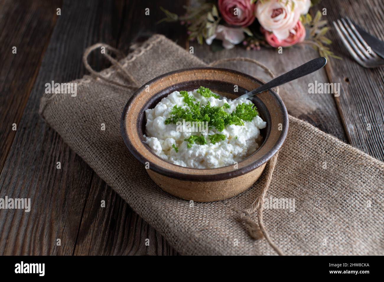 Formaggio casolare con erbe servite con cucchiaio in una rustica ciotola di gres Foto Stock