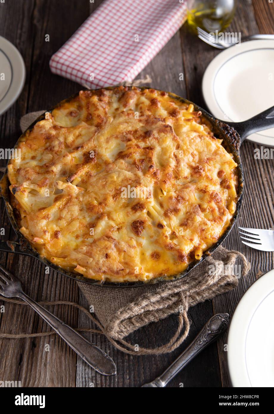 Casseruola di noodle cotta con macaroni, salsa bolognese e bechamel e condita con formaggio, servita su tavola rustica e in legno. Immagine verticale Foto Stock