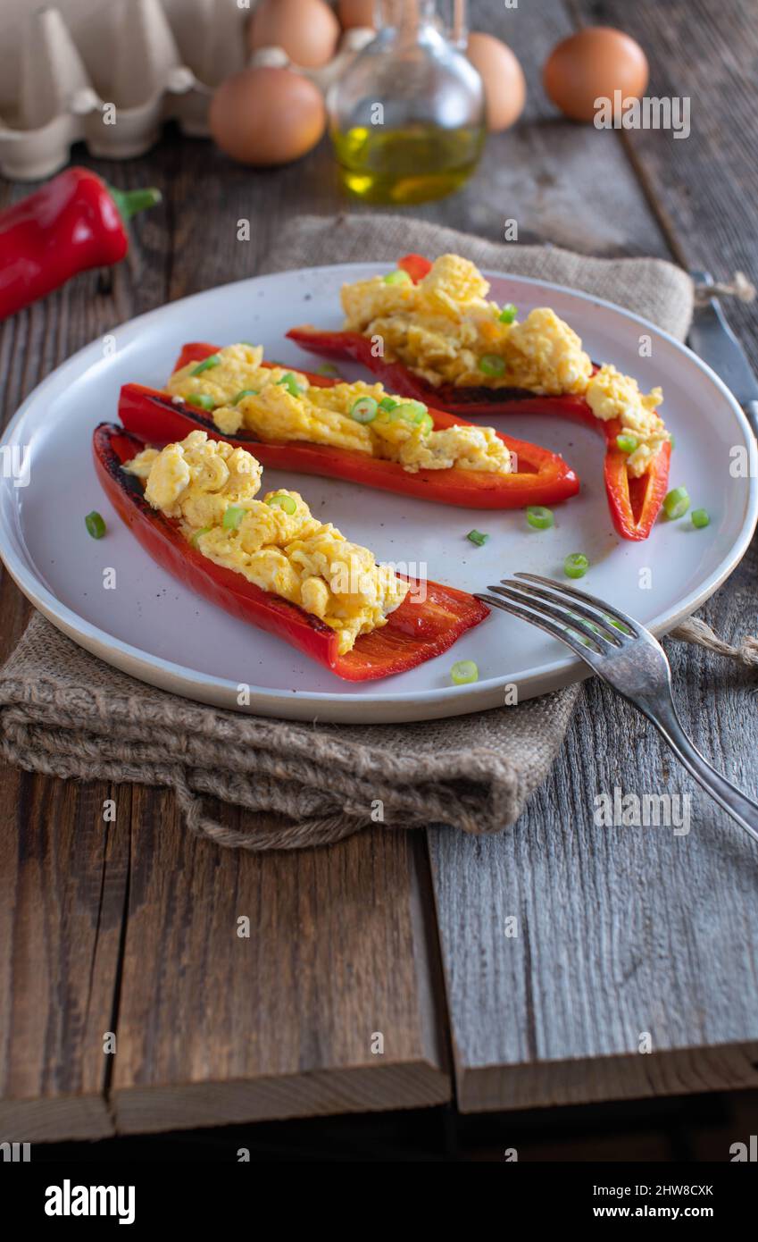 Colazione a base di carb con peperoni rossi arrostiti ripieni di uova strapazzate Foto Stock
