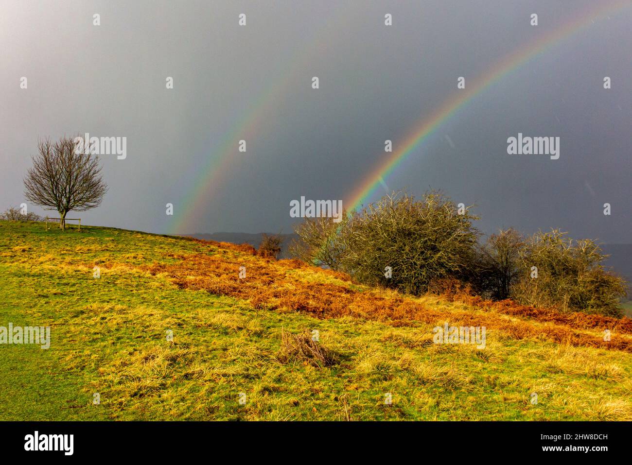 Arcobaleno e cielo scuro con campagna ondulata vicino a Oaker nella zona di Derbyshire Dales del Peak District National Park, Derbyshire, Inghilterra, Regno Unito Foto Stock