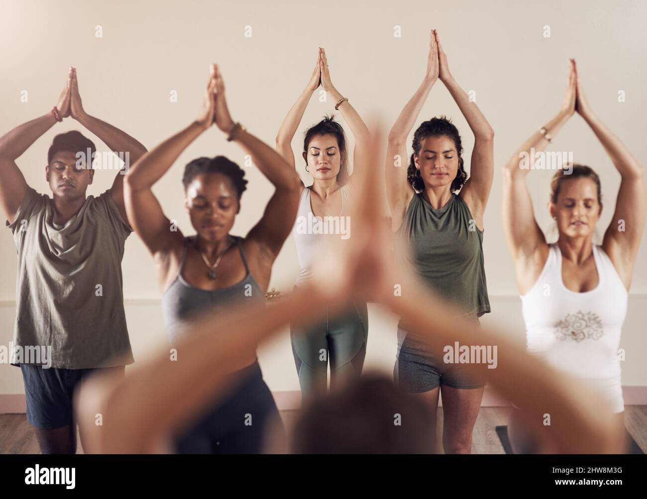 Lo zen è nell'aria. Shot di un gruppo di giovani che lavorano insieme in una lezione di yoga. Foto Stock