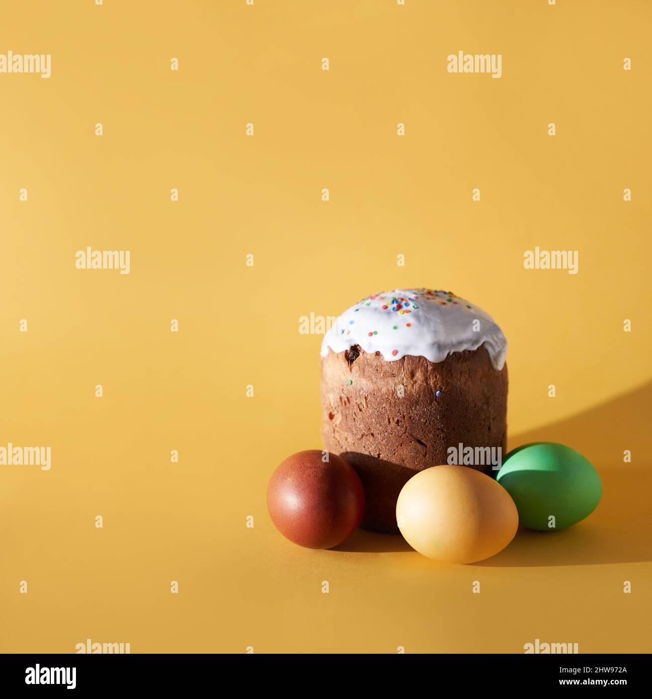 Primo piano di uova di Pasqua colorate e torta o kulich di pasqua su sfondo giallo. Con uno spazio da copiare. Foto di alta qualità Foto Stock