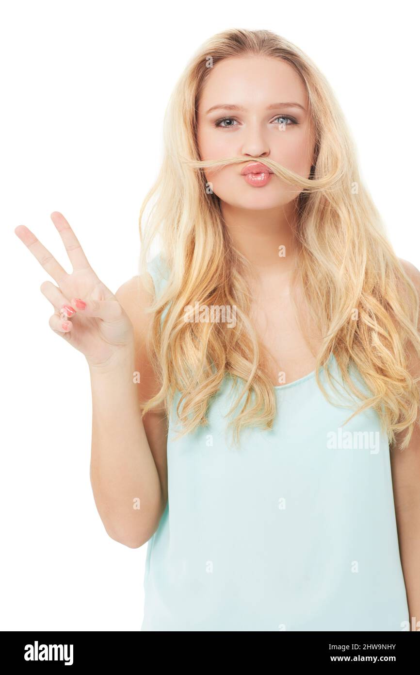 Dare una possibilità alla pace. Una bionda giovane bizzarra che ti mostra un segno di pace con i capelli sopra la bocca - isolato. Foto Stock