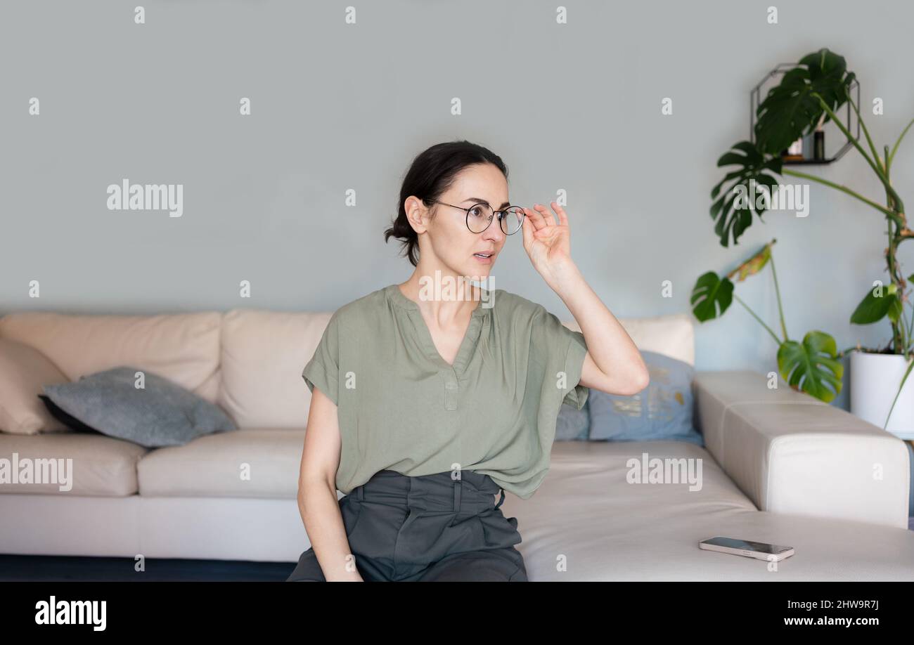 Donna che guarda serio in occhiali con domanda Foto Stock
