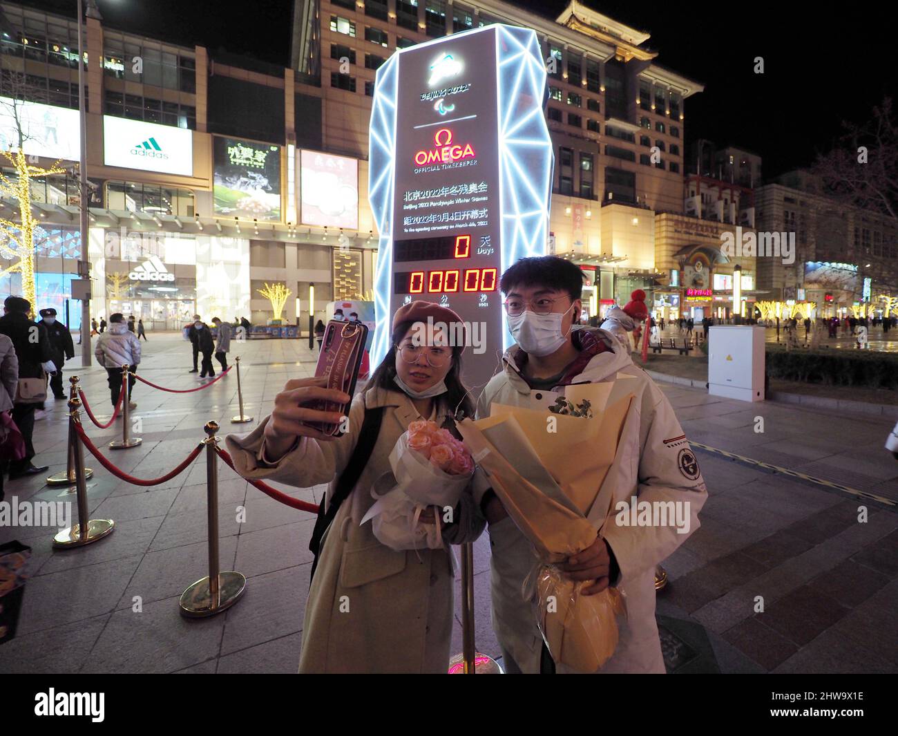 PECHINO, CINA - 4 MARZO 2022 - i cittadini festeggiano l'apertura dei Giochi Paralimpici invernali di fronte a un conto alla rovescia in Wangfujing Street in B. Foto Stock