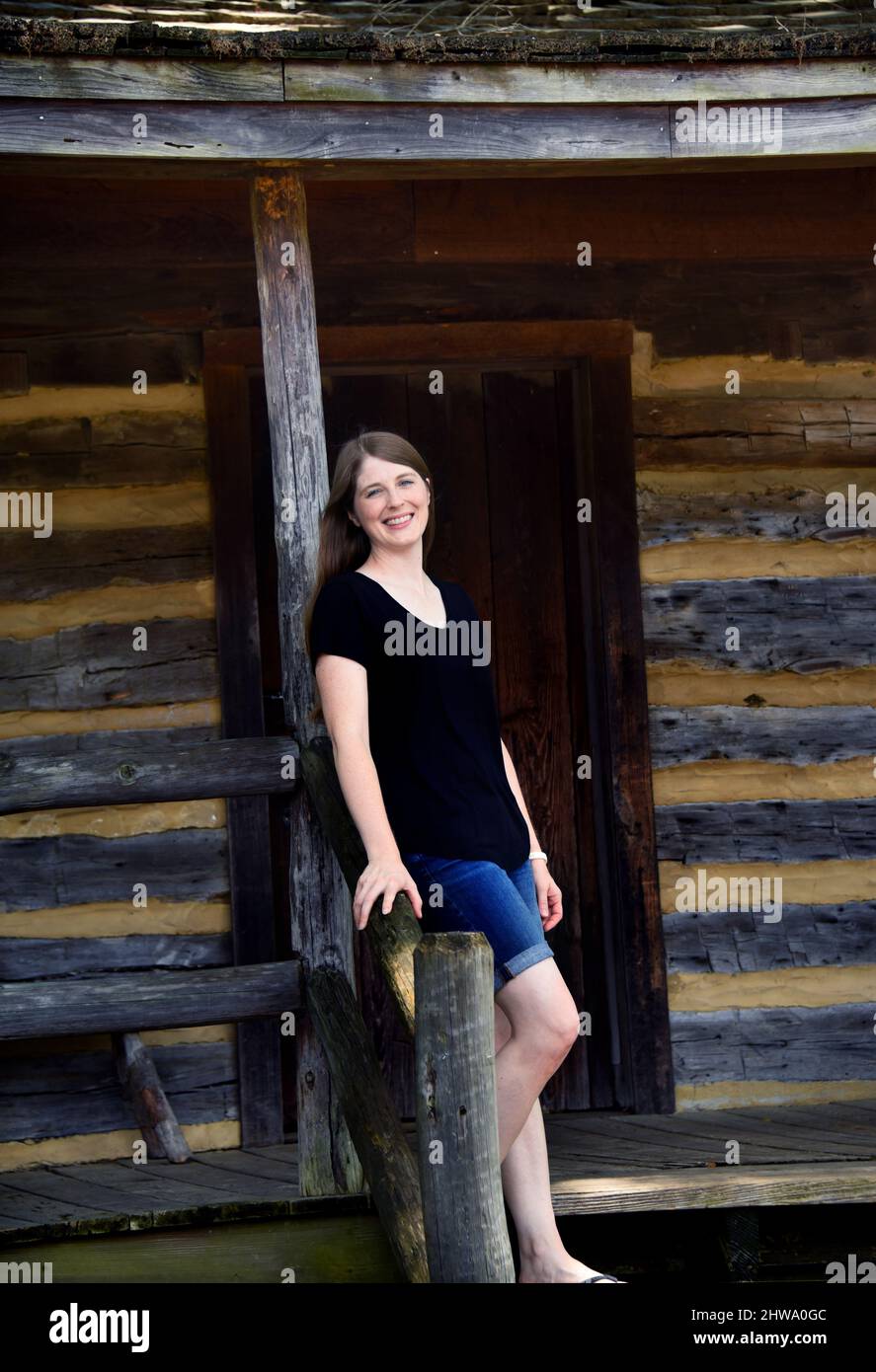 La giovane donna ama visitare la cabina di sosta del pullman sulla piazza di Collierville, Tennessee. È appoggiata contro la ringhiera sul portico anteriore un Foto Stock