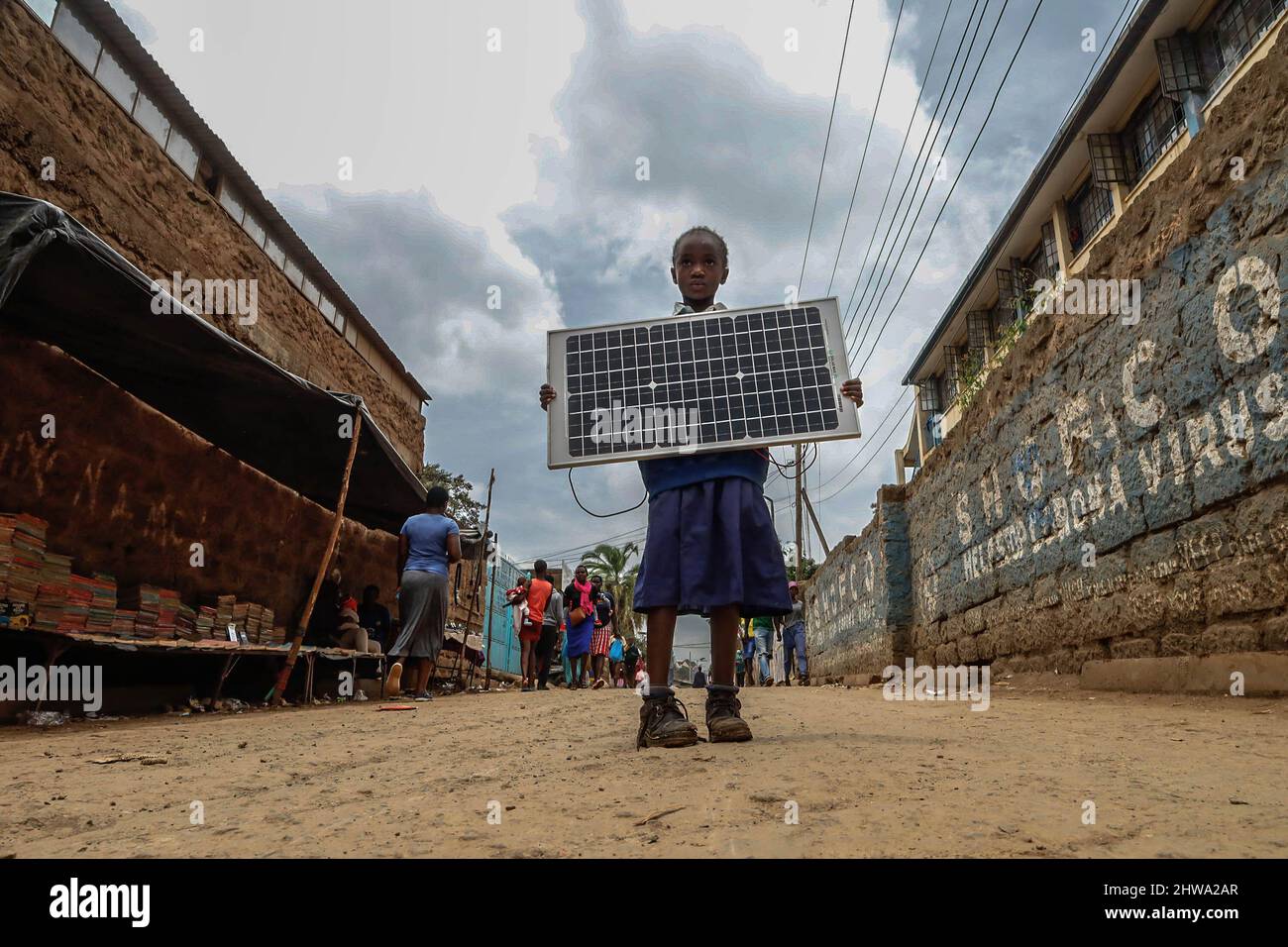 Nairobi, Kenya. 25th Feb 2022. Una giovane ragazza della scuola ha visto trasportare un pannello solare dalle strade in Kibera.in baraccopoli di Kibera, la maggior parte dei residenti specialmente i venditori ambulanti, le scuole private, le organizzazioni non governative, le luci della strada e le scuole stanno usando tutti il sistema di energia solare poco costoso che è una fonte più affidabile ed economica di energia. Ciò ha reso più facile il riciclaggio della maggior parte dell'energia elettrica consumata dai residenti e ha anche contribuito a ridurre l'elevato numero di morti che si verificano a causa delle scosse elettriche e degli incendi di slum quotidiani. (Credit Image: © Donwilson Odhiambo/SOPA Imag Foto Stock