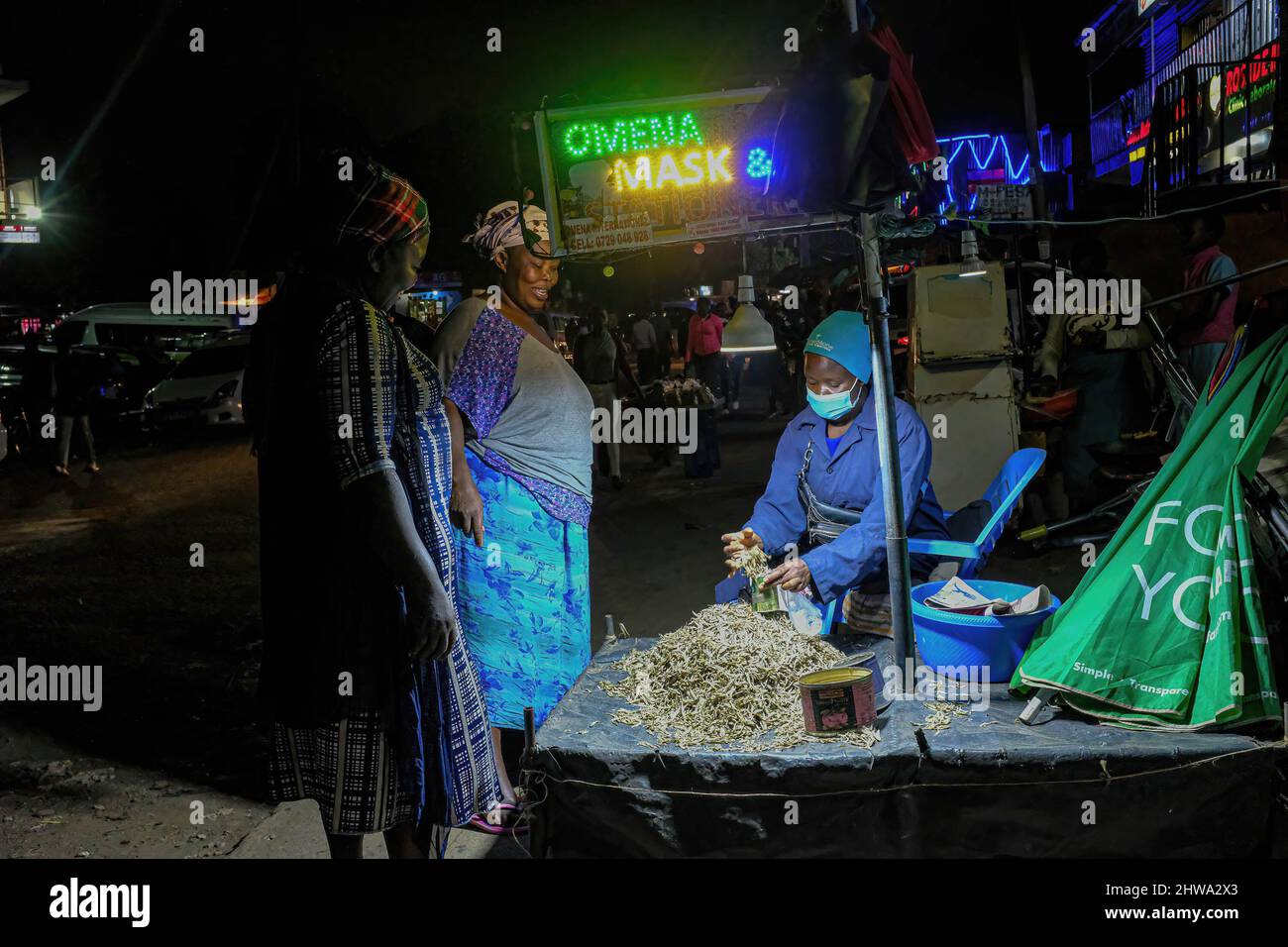 Nairobi, Kenya. 28th Feb 2022. Un venditore di strada che usa una lampada solare mentre fornisce i servizi ai suoi clienti giù dalle strade in baraccopoli di Kibera.in baraccopoli di Kibera, la maggior parte dei residenti specialmente i fornitori di strada, scuole private, organizzazioni non governative, luci di strada, e tutte le scuole utilizzano il sistema di energia solare a basso costo, che è una fonte di energia più affidabile ed economica. Ciò ha reso più facile il riciclaggio della maggior parte dell'energia elettrica consumata dai residenti e ha anche contribuito a ridurre l'elevato numero di morti che si verificano a causa delle scosse elettriche e degli incendi di slum quotidiani. (Credi Foto Stock