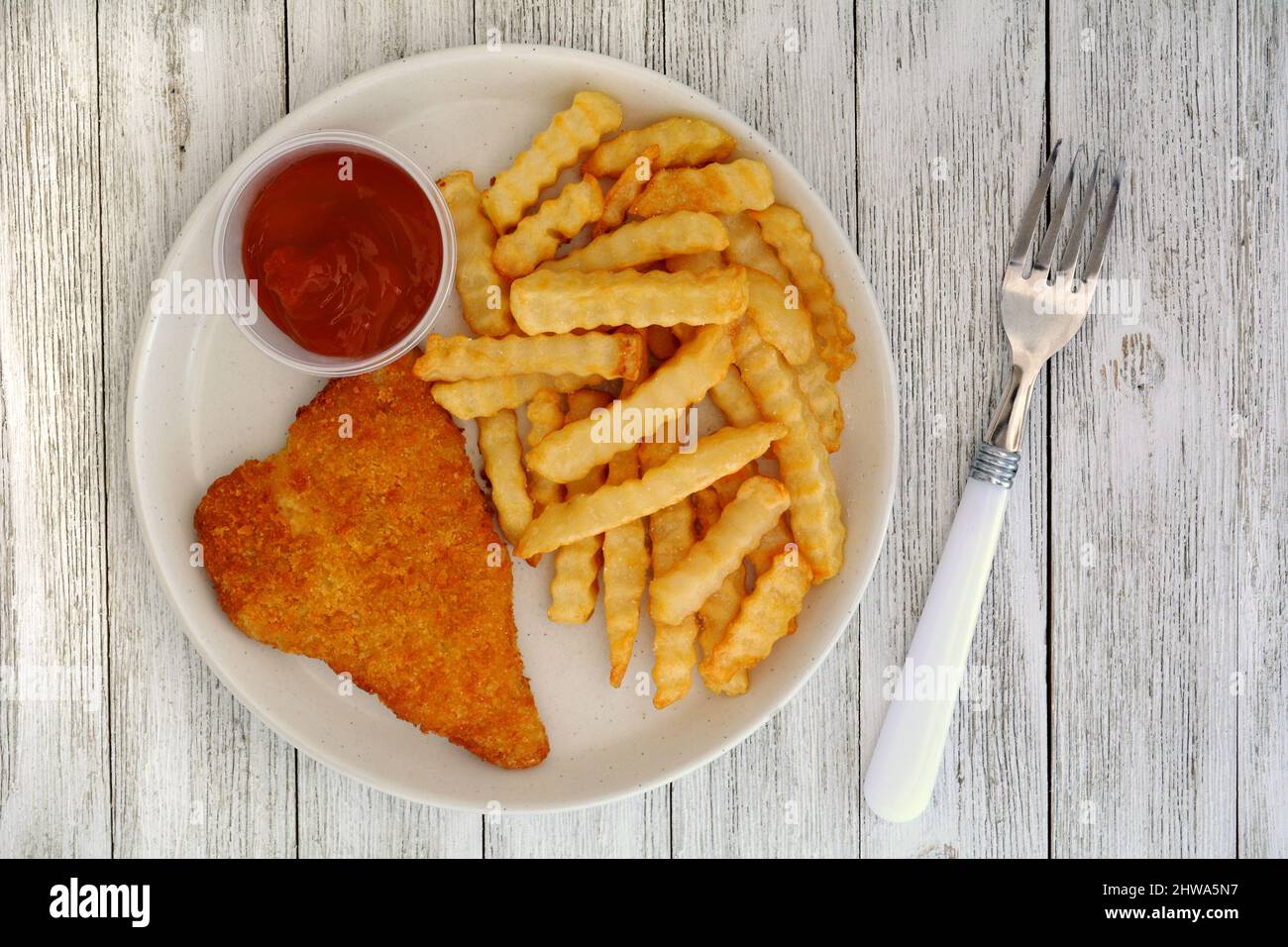 Pesce e patatine casalinghe con ketchup al pomodoro in forma piatta su tavole rustiche dipinte di bianco. Piatti caldi croccanti dorati comfort. Foto Stock