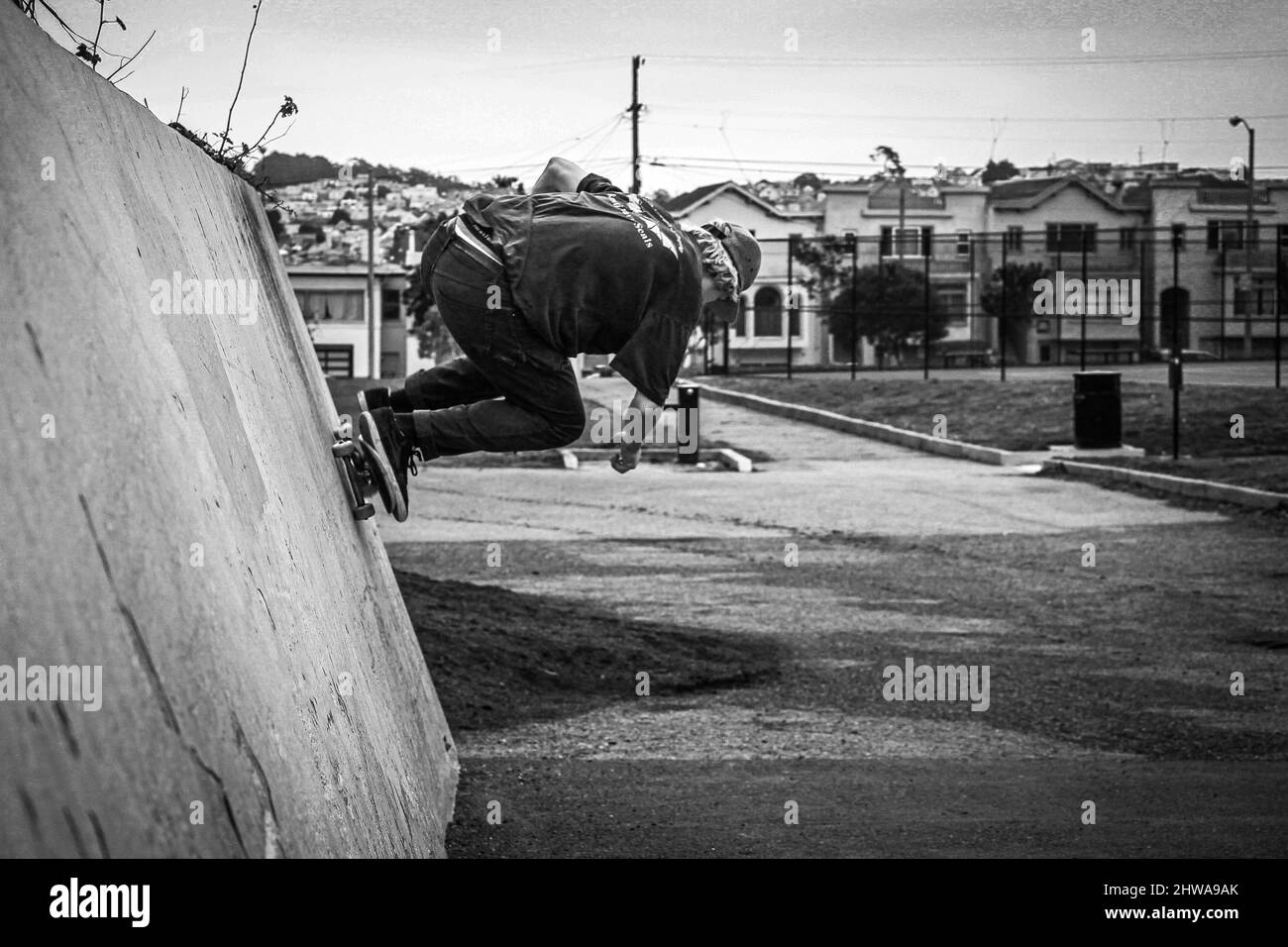 Scala di grigi di uno skateboard che esegue il trucco sul muro nel quartiere di San Francisco Foto Stock