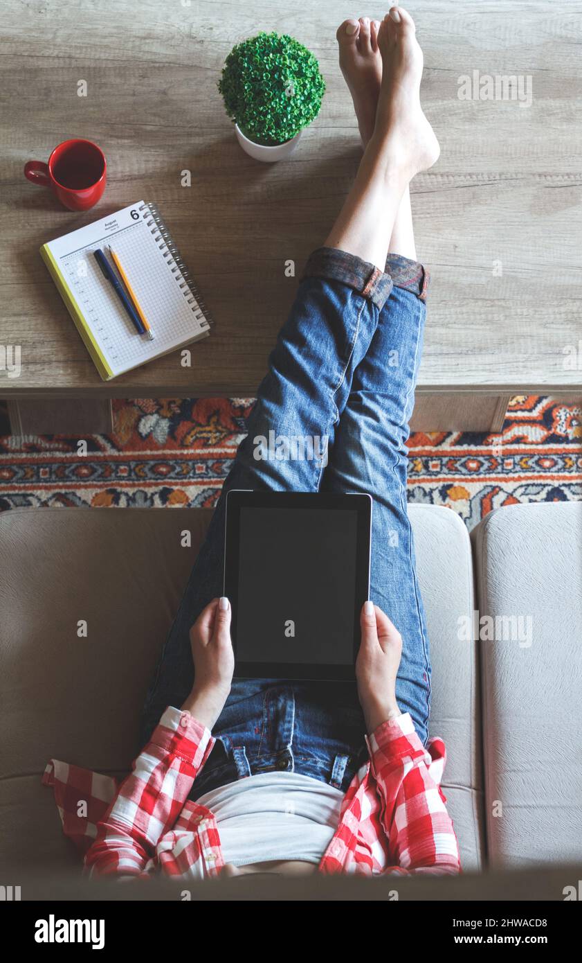 La donna seduta sul divano usa un tablet Foto Stock