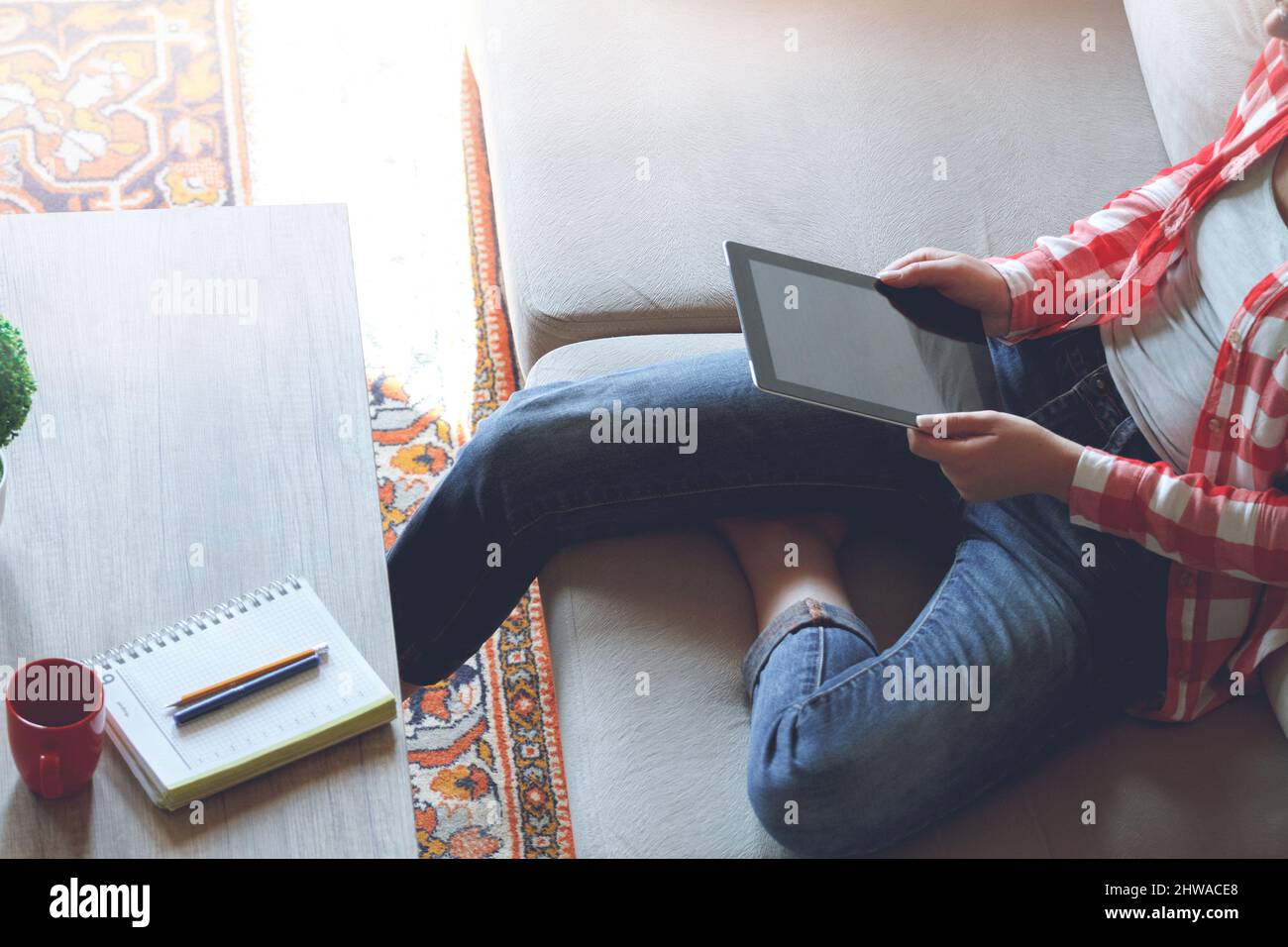 La donna seduta sul divano usa un tablet Foto Stock