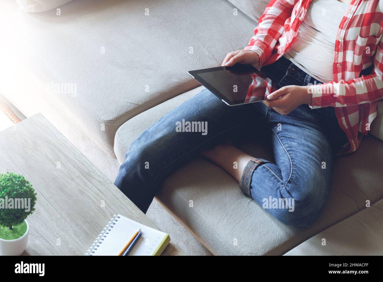 La donna seduta sul divano usa un tablet Foto Stock