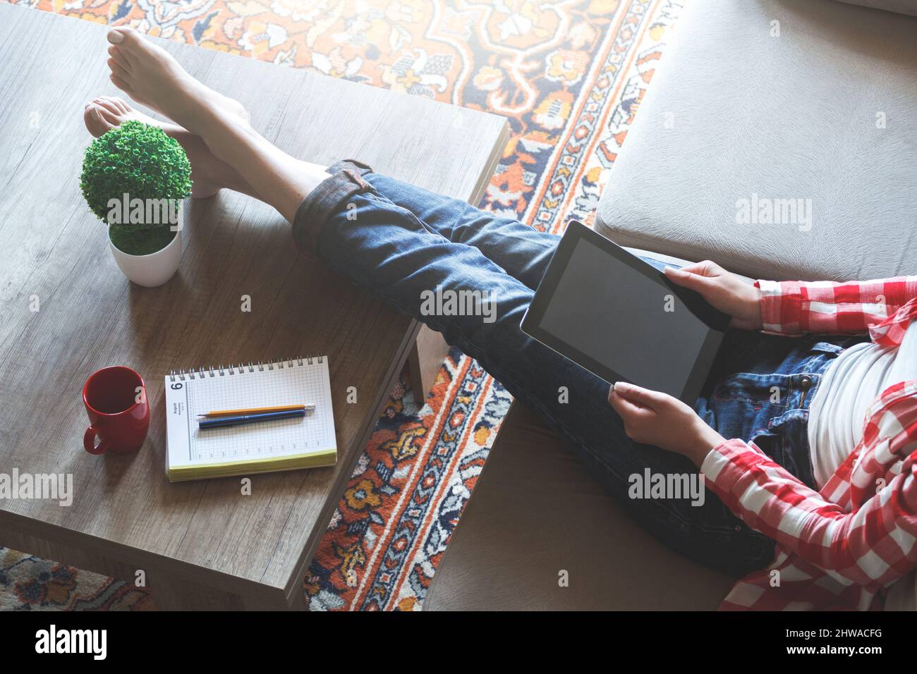 La donna seduta sul divano usa un tablet Foto Stock