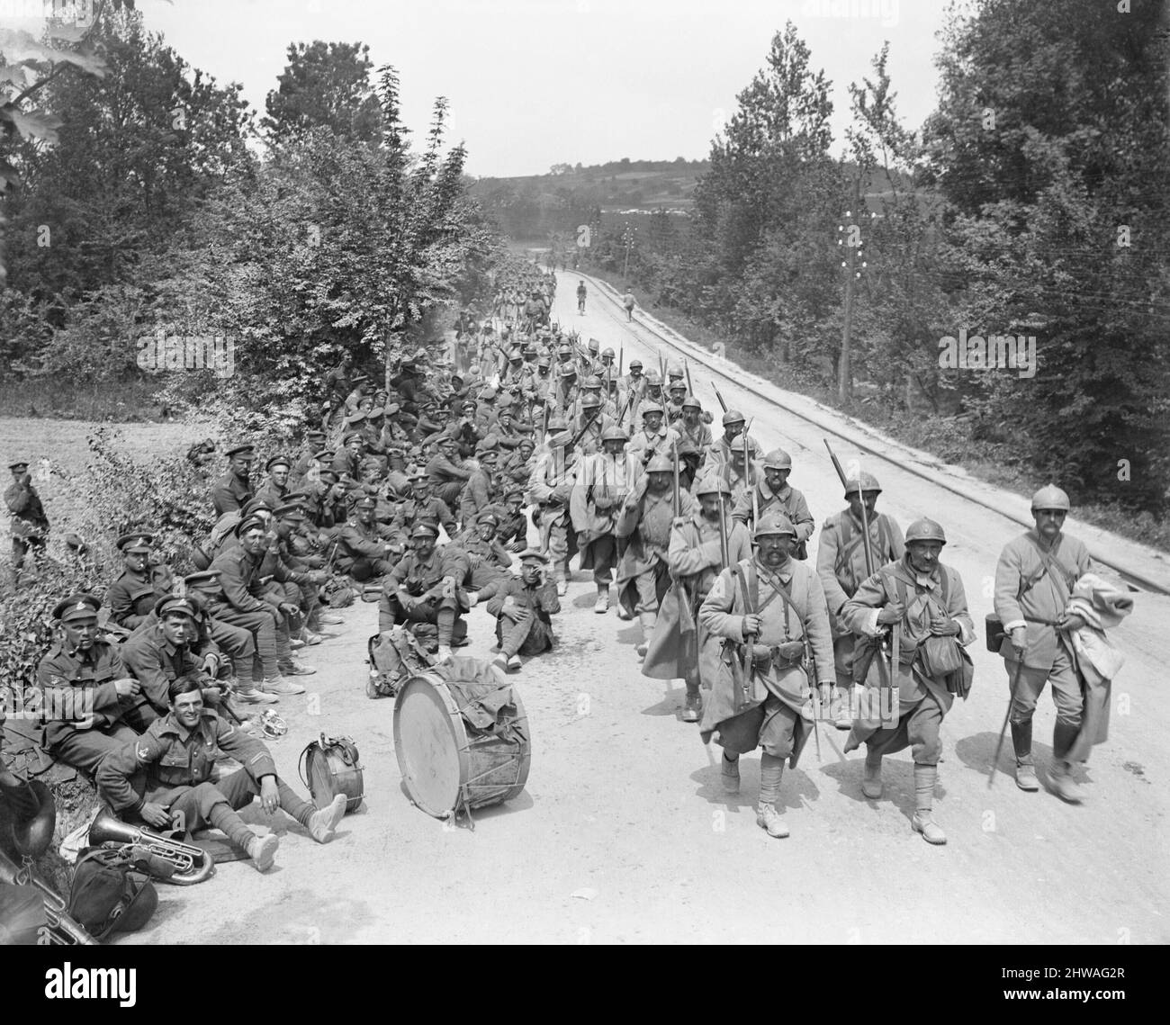 La fanteria francese che torna attraverso Passy-sur-Marne passa la banda reggimentale britannica che riposa sulla strada, 29 maggio 1918 durante la battaglia dell'Aisne Foto Stock