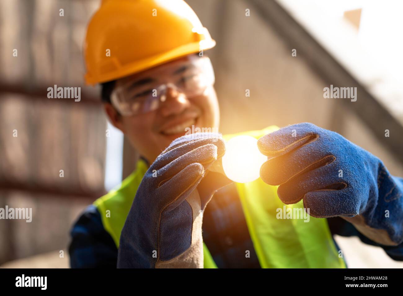 Asian felice elettricista con lampadine e fissare la luce all'interno appartamento ristrutturato in cantiere. Foto Stock