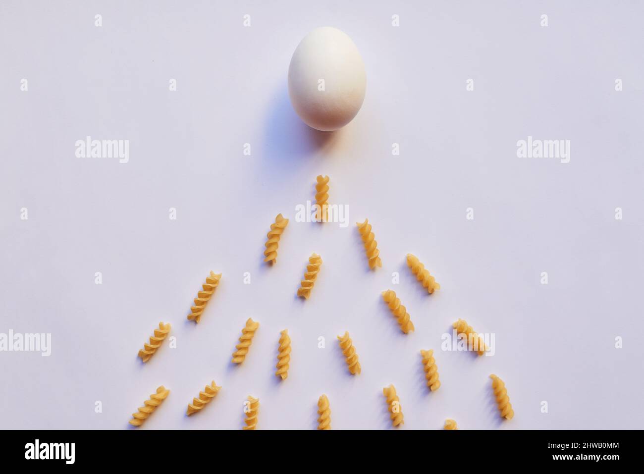 Ultimo c'è un uovo marcio. Lo studio ha sparato un uovo su sfondo grigio mentre è circondato da un sacco di piccoli pezzi di pasta. Foto Stock Ultimo c'è un uovo marcio. Lo studio ha sparato un uovo su sfondo grigio mentre è circondato da un sacco di piccoli pezzi di pasta. Foto Stock