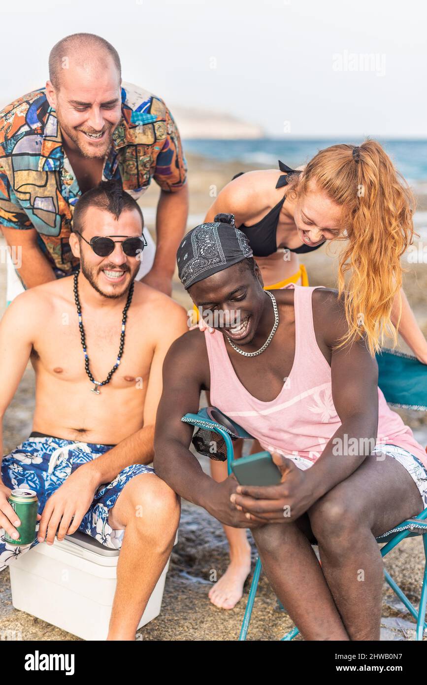 quattro amici multirazziali che hanno un buon tempo in spiaggia Foto Stock