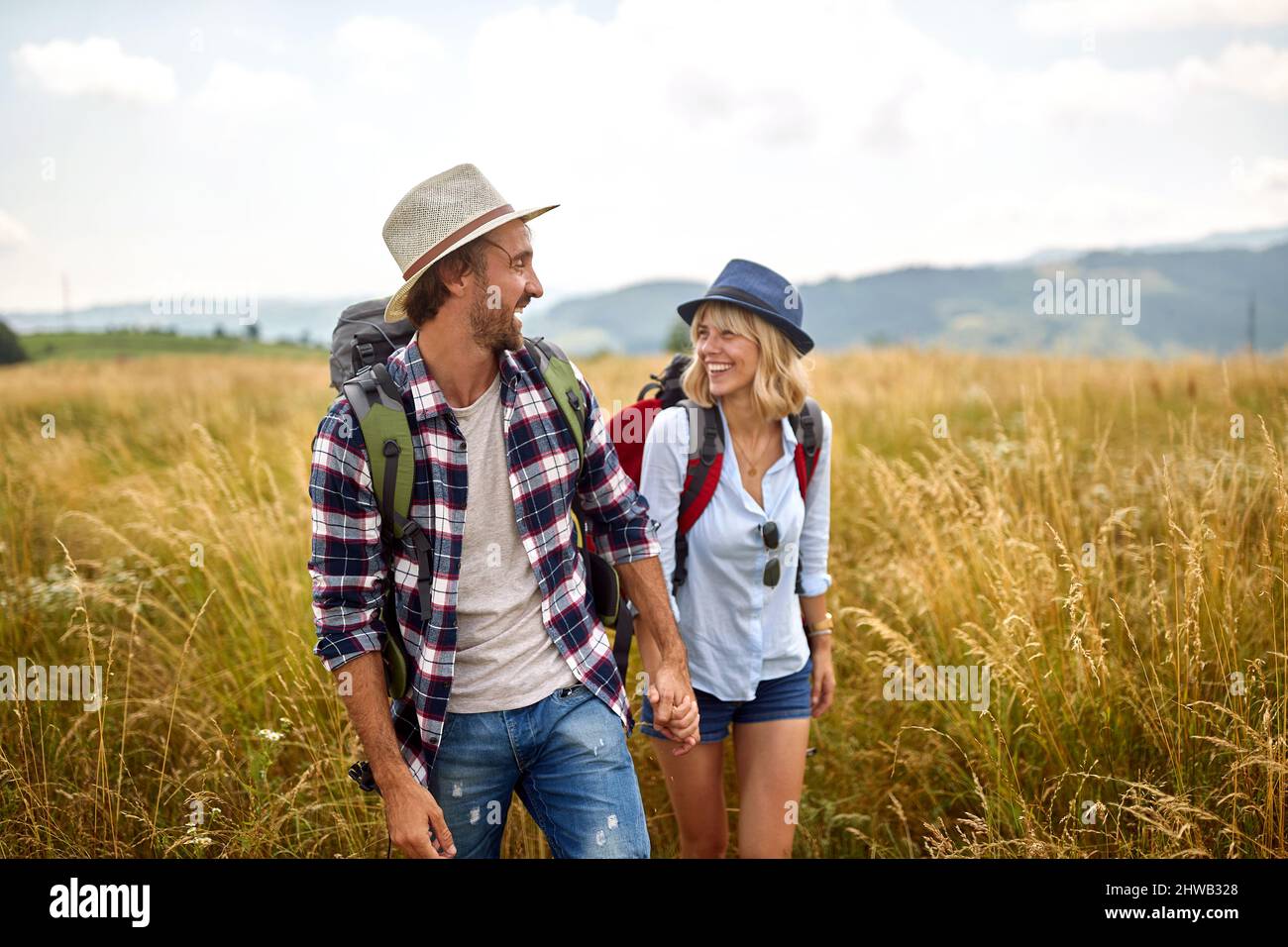 giovane coppia sorridente che si muove in campagna. felice gente che viaggia nella natura Foto Stock