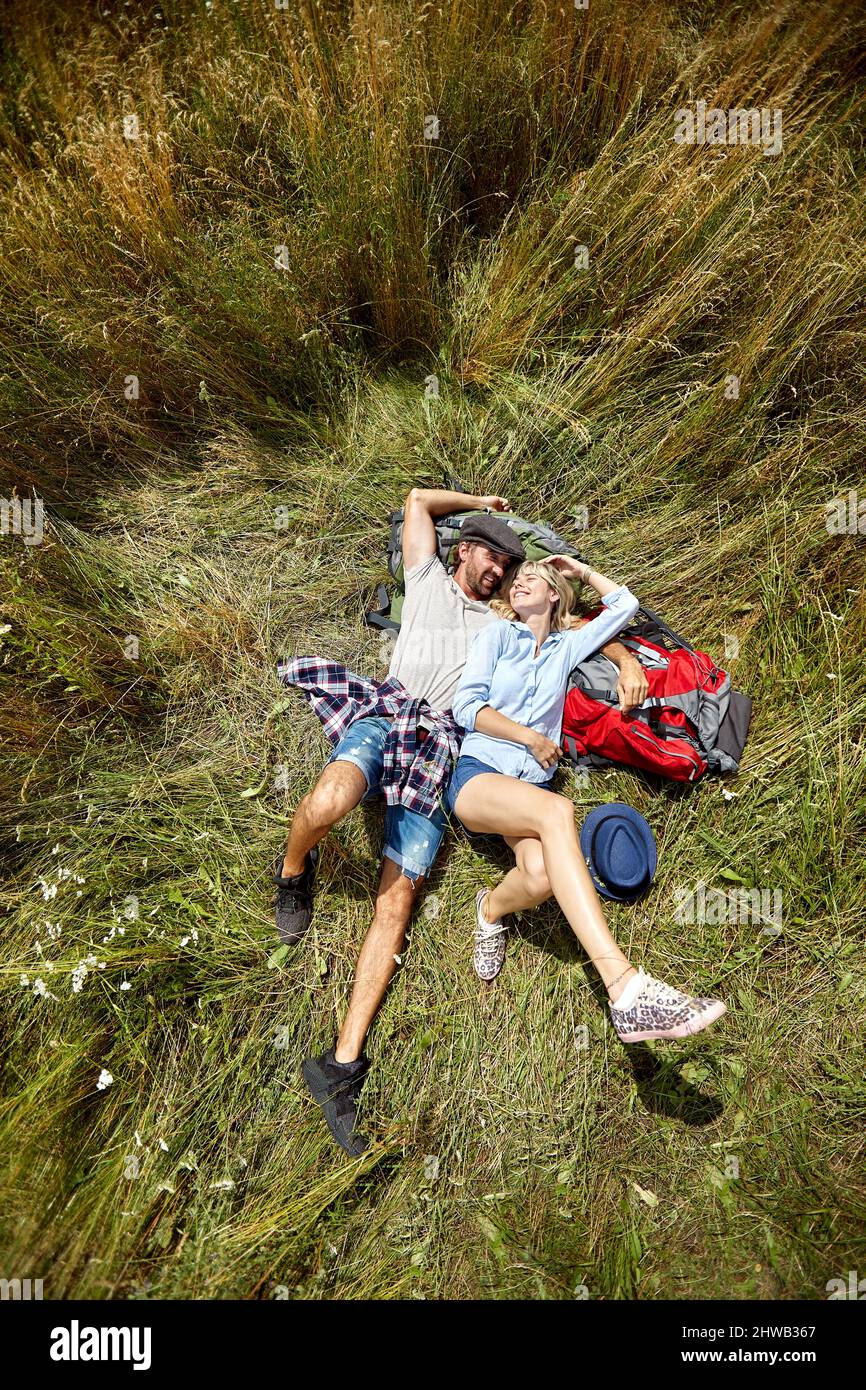 Amorevole coppia abbracciante adagiato sull'erba e divertendosi insieme nella natura Foto Stock