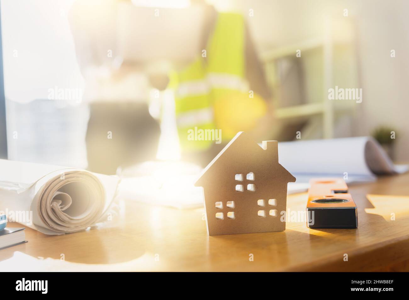 ingegnere planare e controllare su blueprint su sfondo tavolo di piccolo modello casa, concetto immobiliare Foto Stock