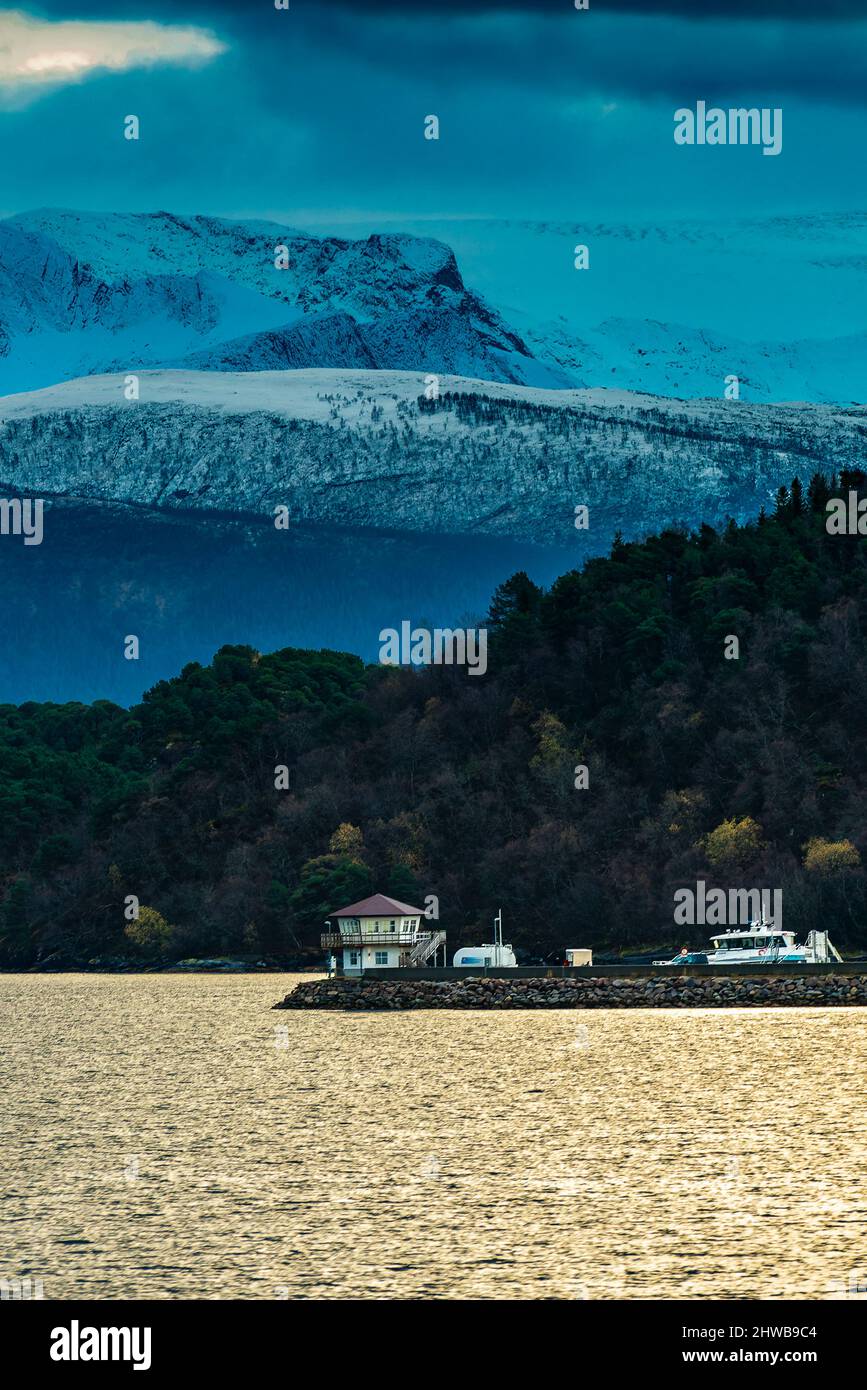 kleines Dorf an der norwegischen Küste in der Gegend von tons, mit schneebedeckten Bergen im Hintergrund und Schwartisen Gletscher, in Wolken gehüllt. Foto Stock