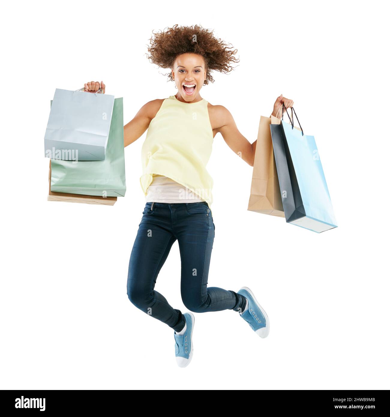 Shopping frenetico. Ritratto di studio di una giovane donna eccitata portando borse shopping e saltare per la gioia su uno sfondo bianco. Foto Stock