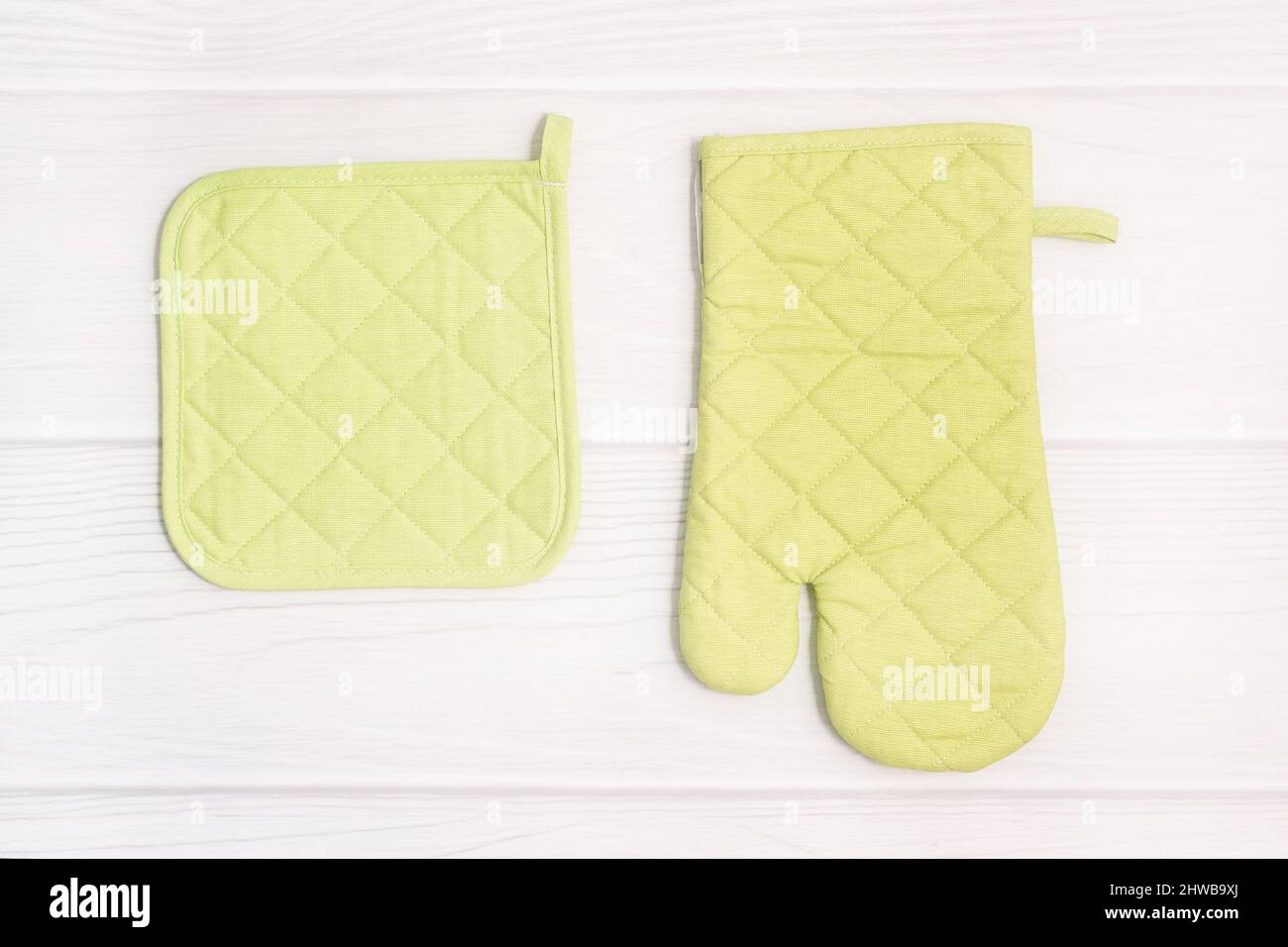 Muffa da forno e potholder su sfondo di legno. Accessorio cucina. Disposizione piatta. Foto Stock