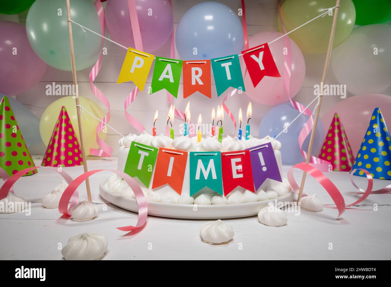 Torta di compleanno con candele bruciate con palloncini sullo sfondo. Torta di compleanno con candele per feste. Foto Stock