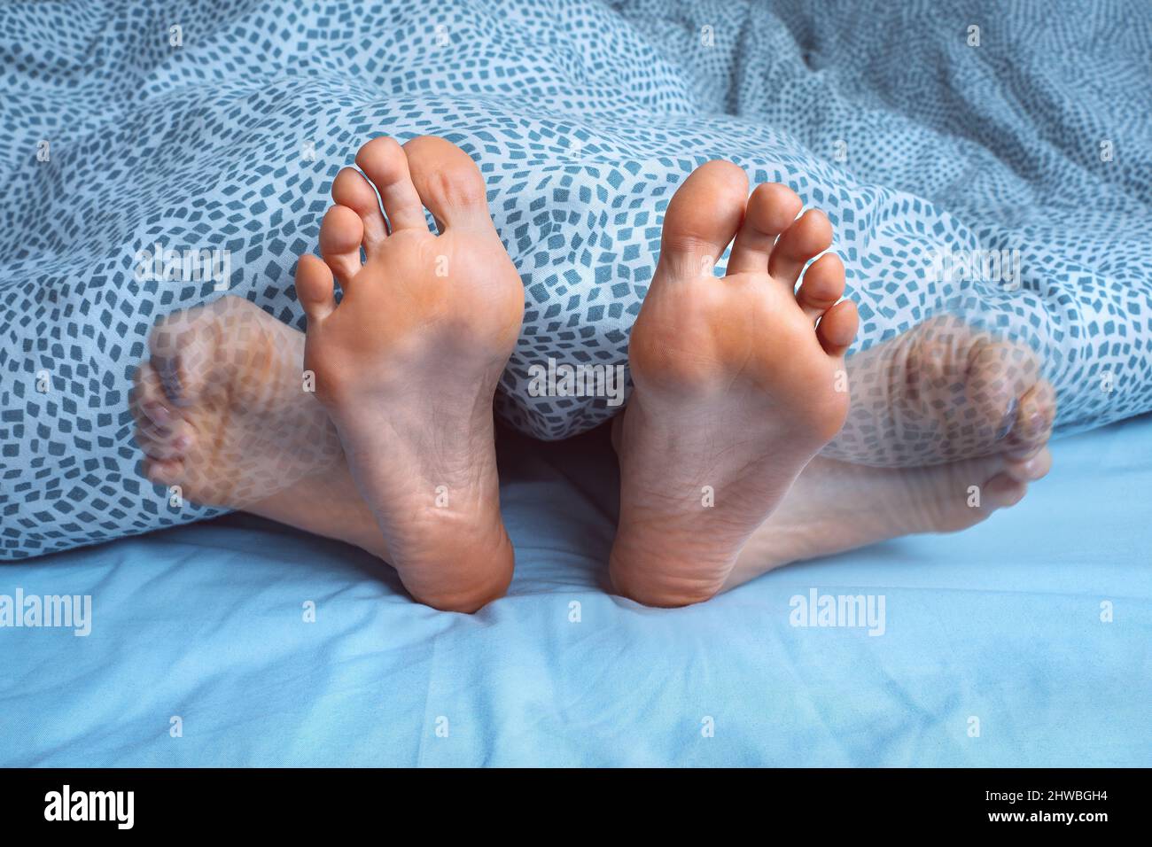 Donna che soffre di crampi ai piedi, crampi alle gambe o spasmi muscolari durante il sonno. Dolore ai piedi o dolore ai piedi durante la notte. Sindrome delle gambe senza riposo Foto Stock