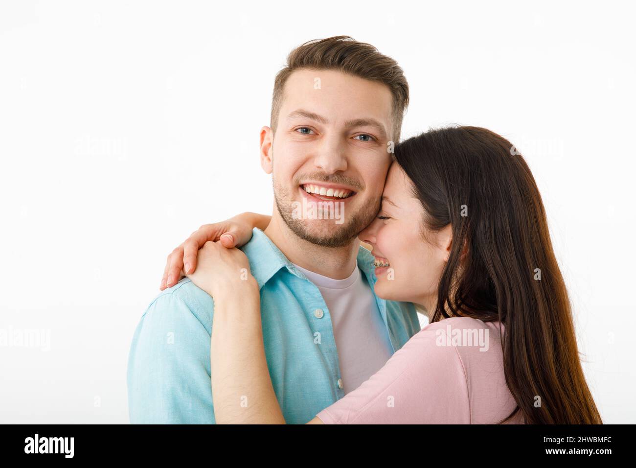 Ritratto di una bella coppia amata. Un ragazzo e una ragazza si abbracciano e guardano la macchina fotografica sorridendo . Su sfondo bianco Foto Stock