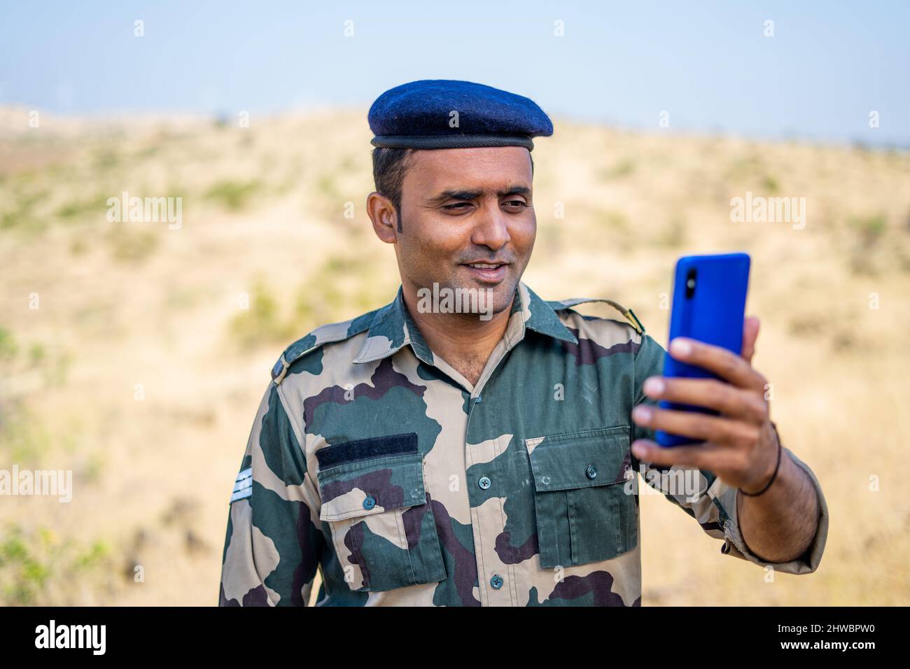 Sorridendo soldati indiani in uniforme facendo videochiamate sul telefono cellulare durante il servizio - concetto di tecnologia, famiglia mancante e relax Foto Stock