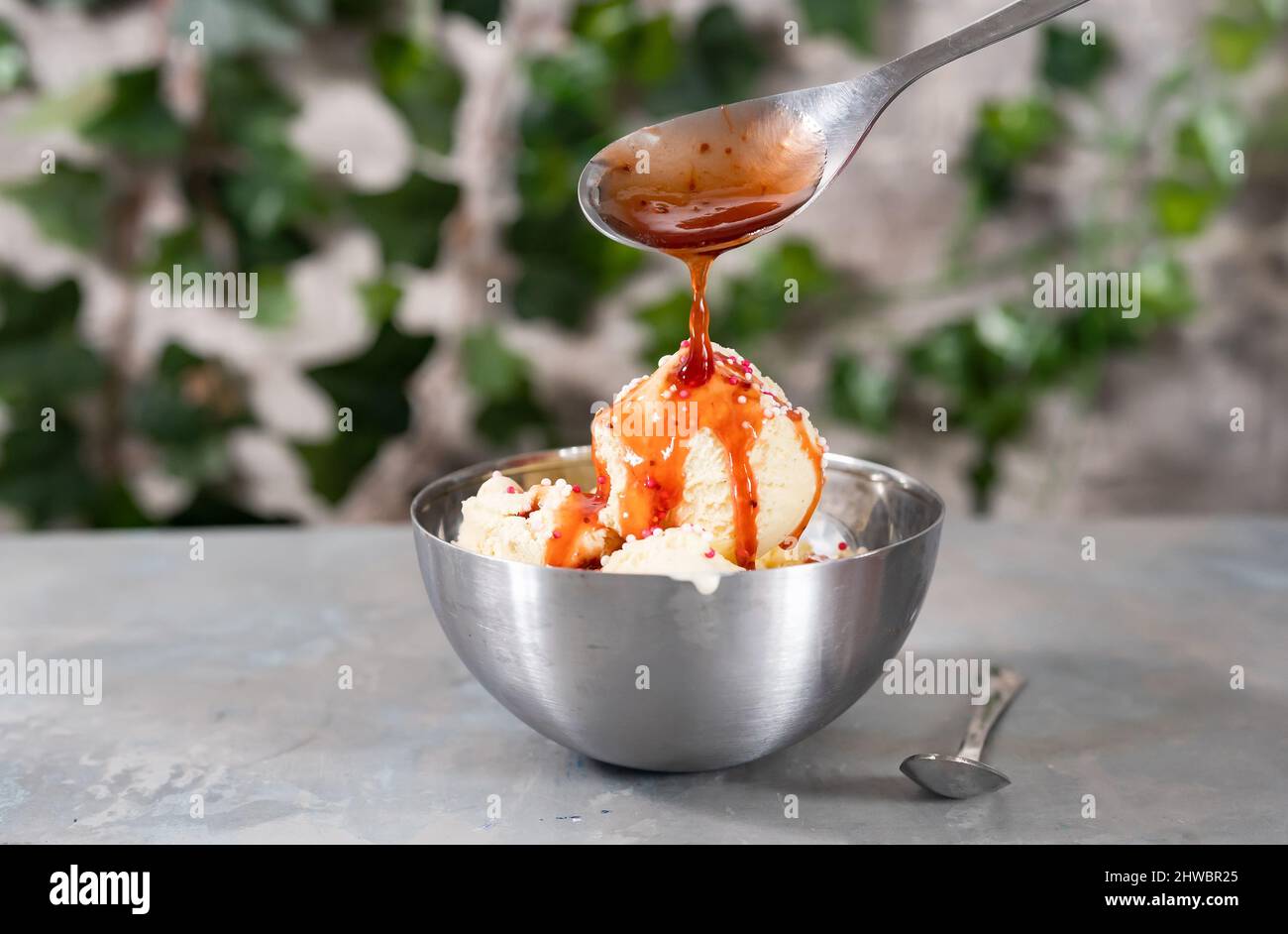 Versare all'aperto le palette per gelato alla vaniglia con salsa di fragole su sfondo verde Foto Stock