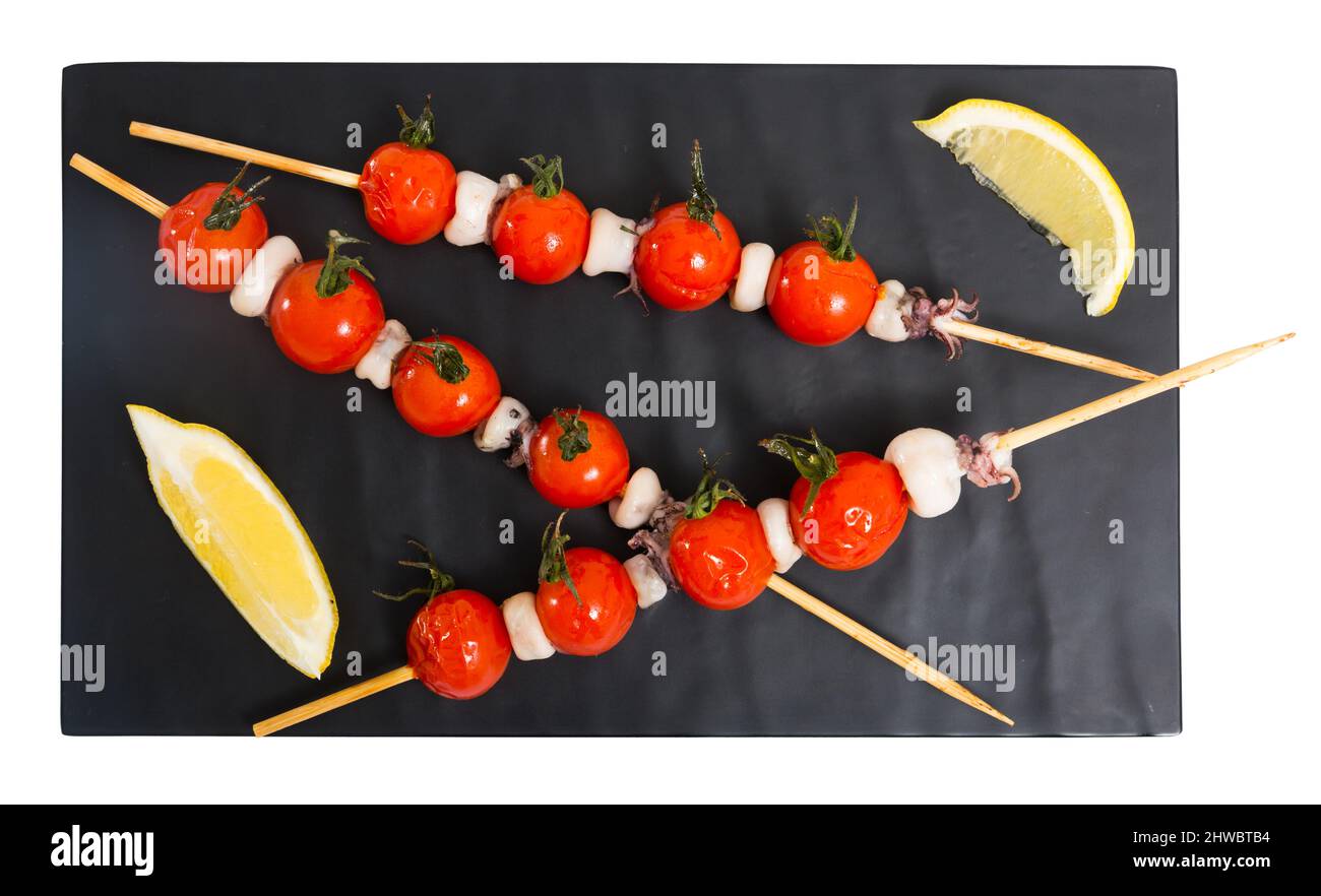 Scheda mini con calamari su spiedini alla griglia con olio di oliva e aceto balsamico con pomodori ciliegia . Isolato su sfondo bianco Foto Stock
