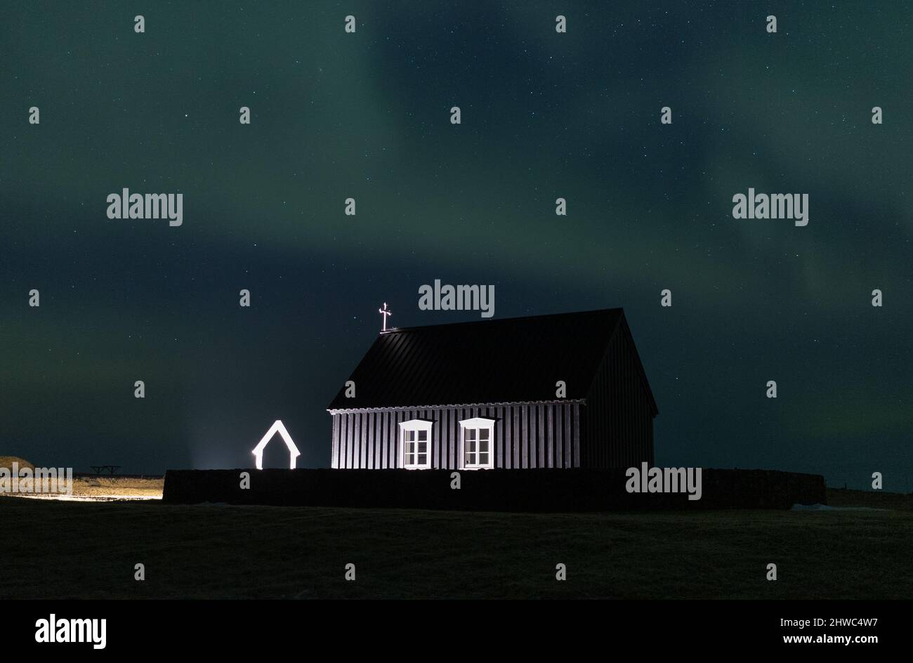 Aurora boreale su una chiesa nera in Islanda Foto Stock