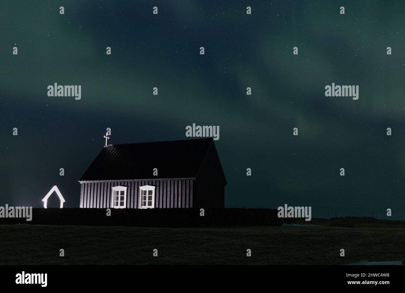 Aurora boreale su una chiesa nera in Islanda Foto Stock