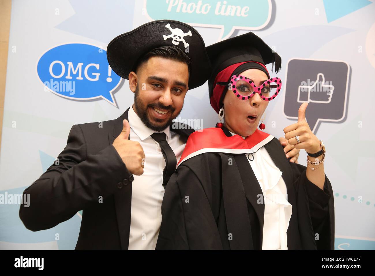 Una bella donna asiatica laureata e partner posa per una divertente fotografia alla sua cerimonia di laurea. Questo evento formale in cui si laurea (prima) chang Foto Stock