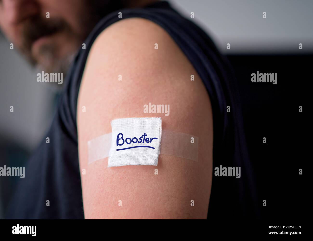 Uomo vaccinato che guarda verso il basso il cerotto in gesso sulla spalla subito dopo avere ottenuto il vaccino del covid-19. Concetto di colpo di richiamo. Foto di alta qualità Foto Stock