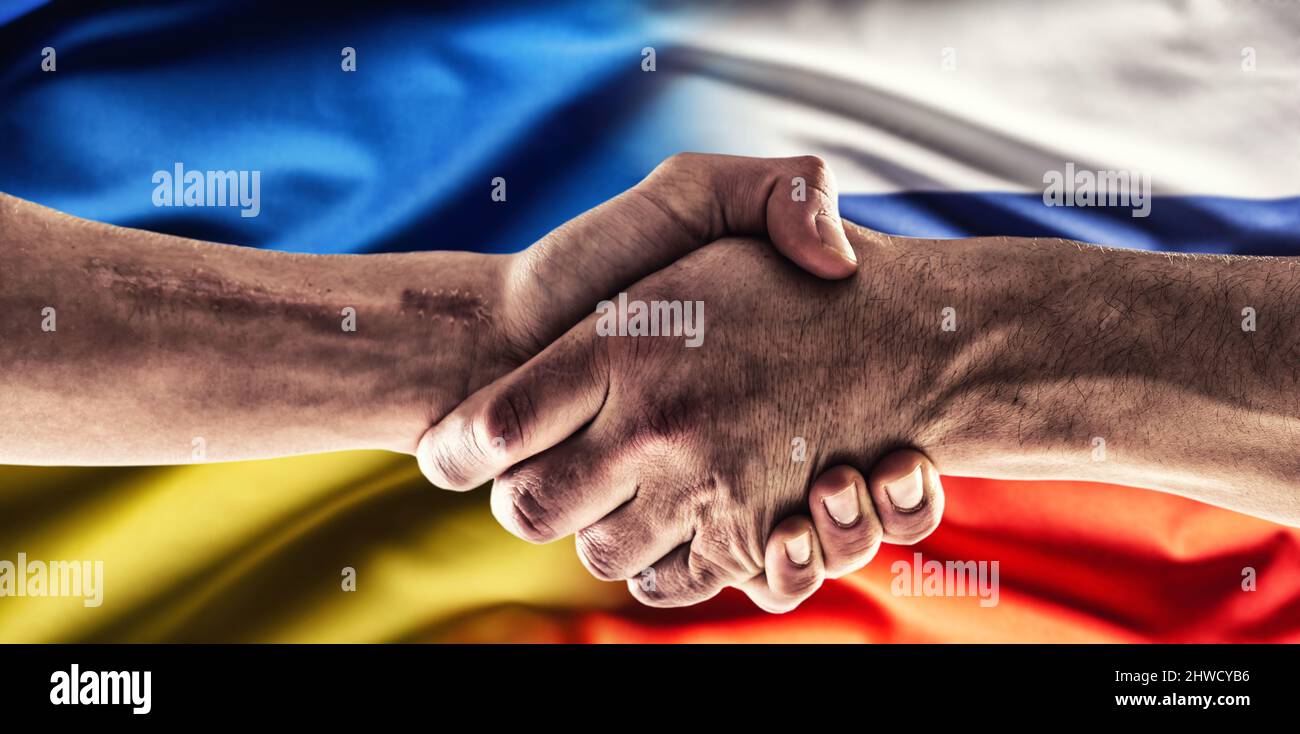 Una stretta di mano sopra le bandiere ucraine e russe. Foto Stock