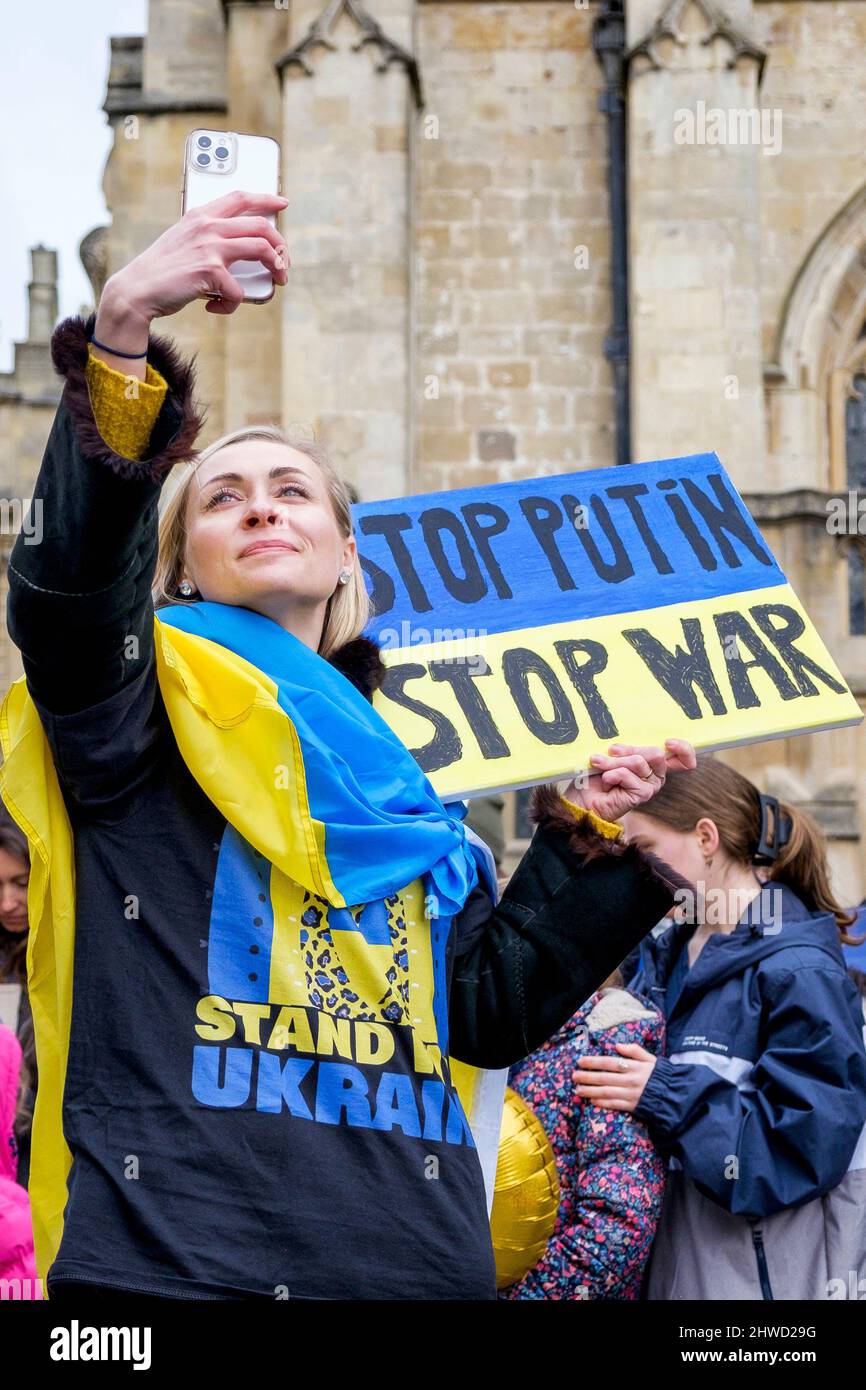Bath, Regno Unito. 5th marzo 2022. Una donna drapponata alla bandiera Ucraina prende un selfie di fronte all'Abbazia di Bath durante una dimostrazione contro l'invasione russa dell'Ucraina. La manifestazione è stata organizzata per consentire alla popolazione locale di dimostrare la propria solidarietà con l'Ucraina nella guerra Russia-Ucraina e condannare le azioni di Putin. Credit: Lynchpics/Alamy Live News Foto Stock