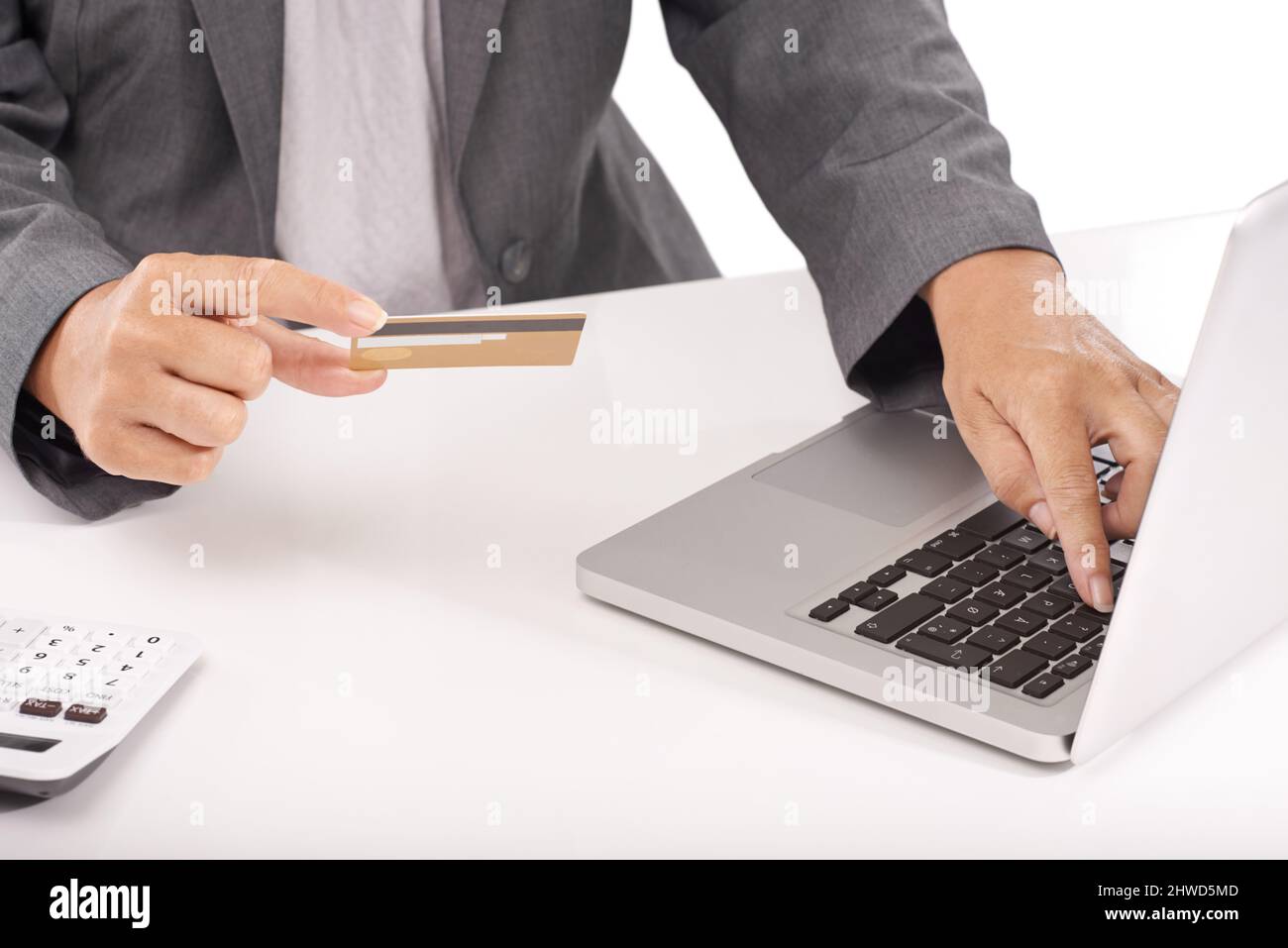 Risparmiate tempo con l'internet banking. Un primo piano di una donna in viaggio d'affari che tiene la sua carta di credito mentre lavora sul suo laptop. Foto Stock