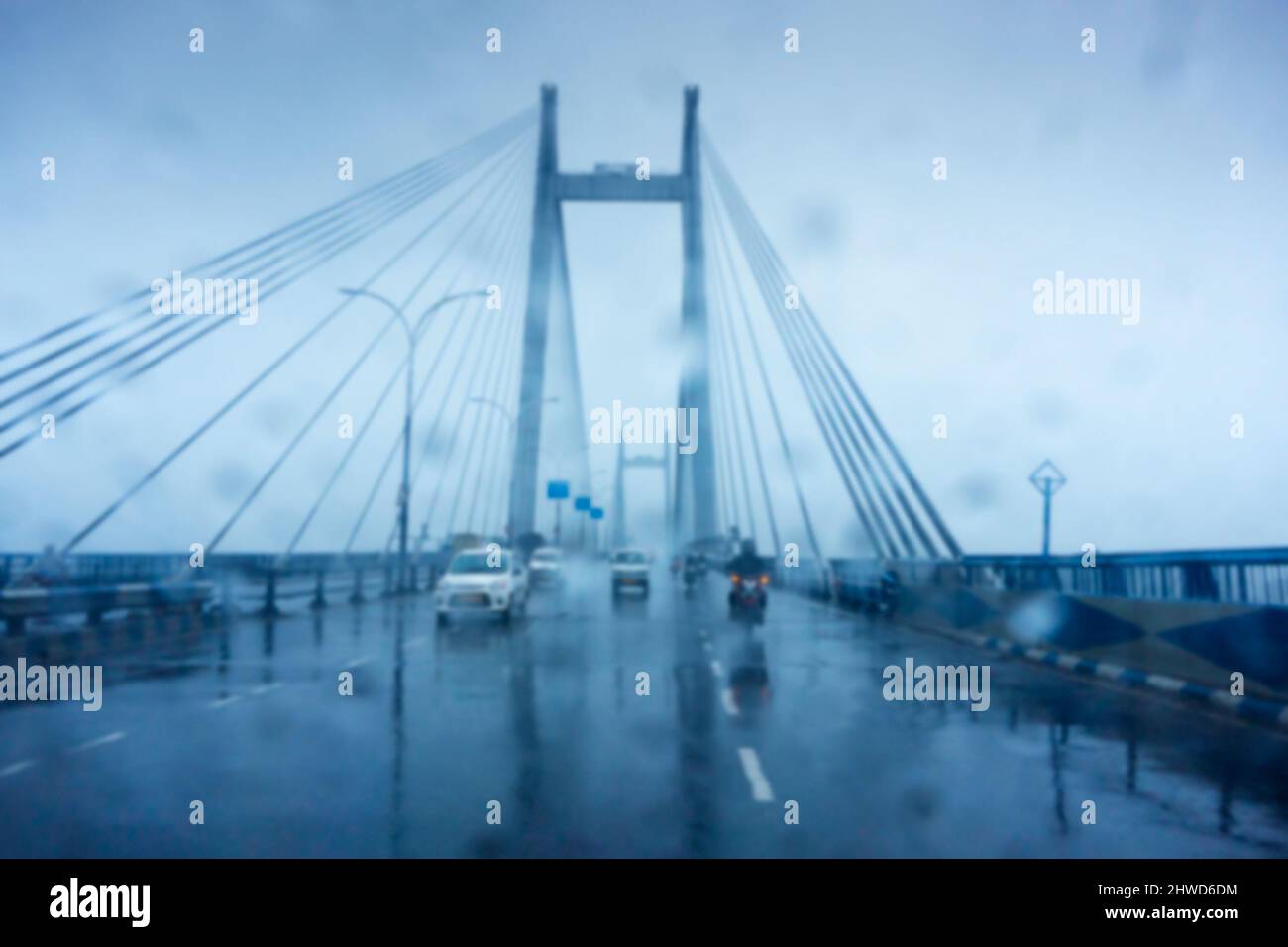 Immagine sfocata, immagine scattata attraverso le gocce d'acqua che cadono sul parabrezza dell'automobile, vetro bagnato, traffico a 2nd ponte di Hoogly. Immagine stock monsone. Foto Stock
